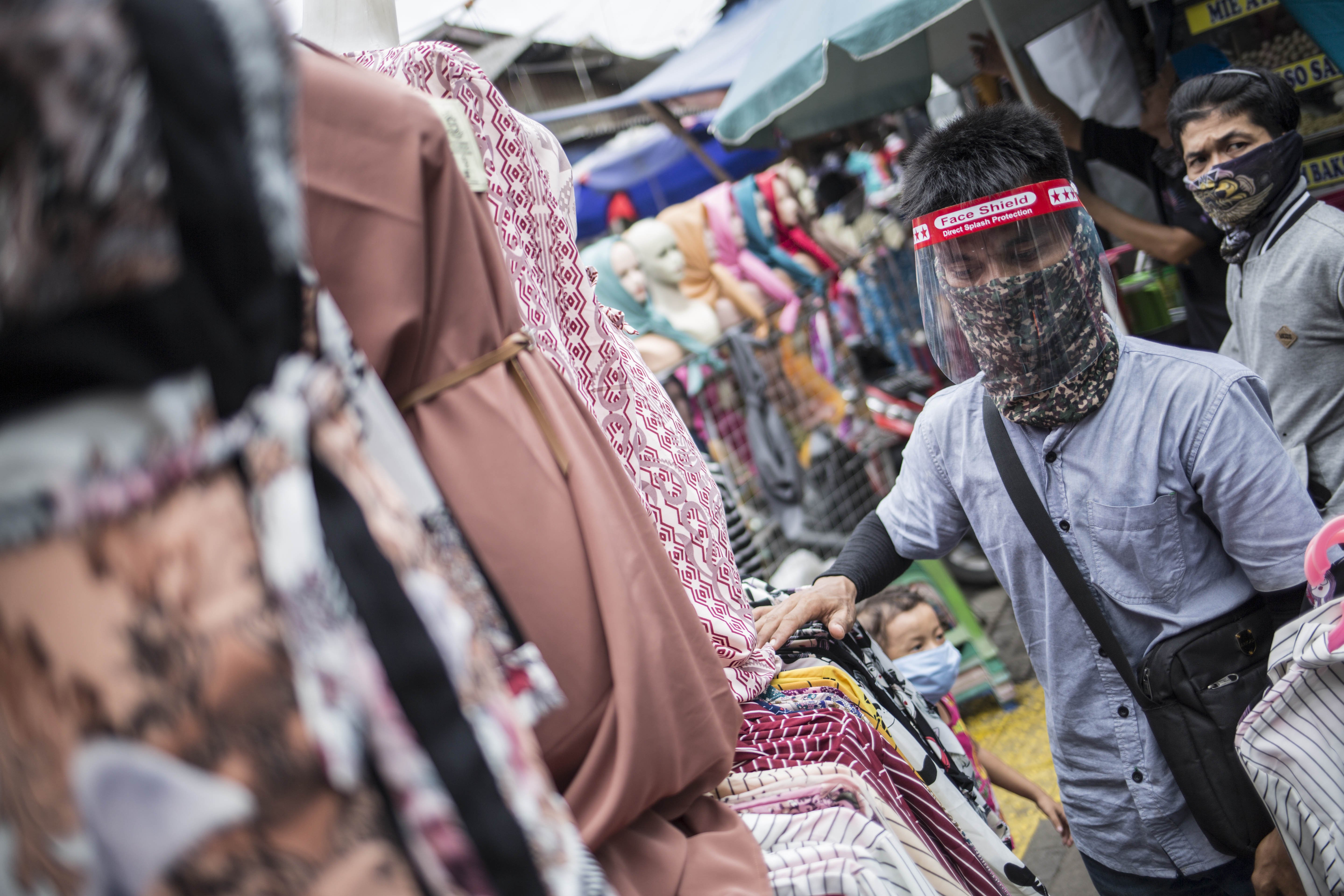Pedagang menggunakan face shield saat melayani pembeli di Kawasan Pasar Tanah Abang, Jakarta, Senin (18/5/2020). Meski kawasan niaga Pasar Tanah Abang telah tutup selama masa Pembatasan Sosial Berskala Besar (PSBB), namun sebagian pedagang tetap menggelar lapaknya di sejumlah titik seperti di atas trotoar dan di gang perkampungan setempat.