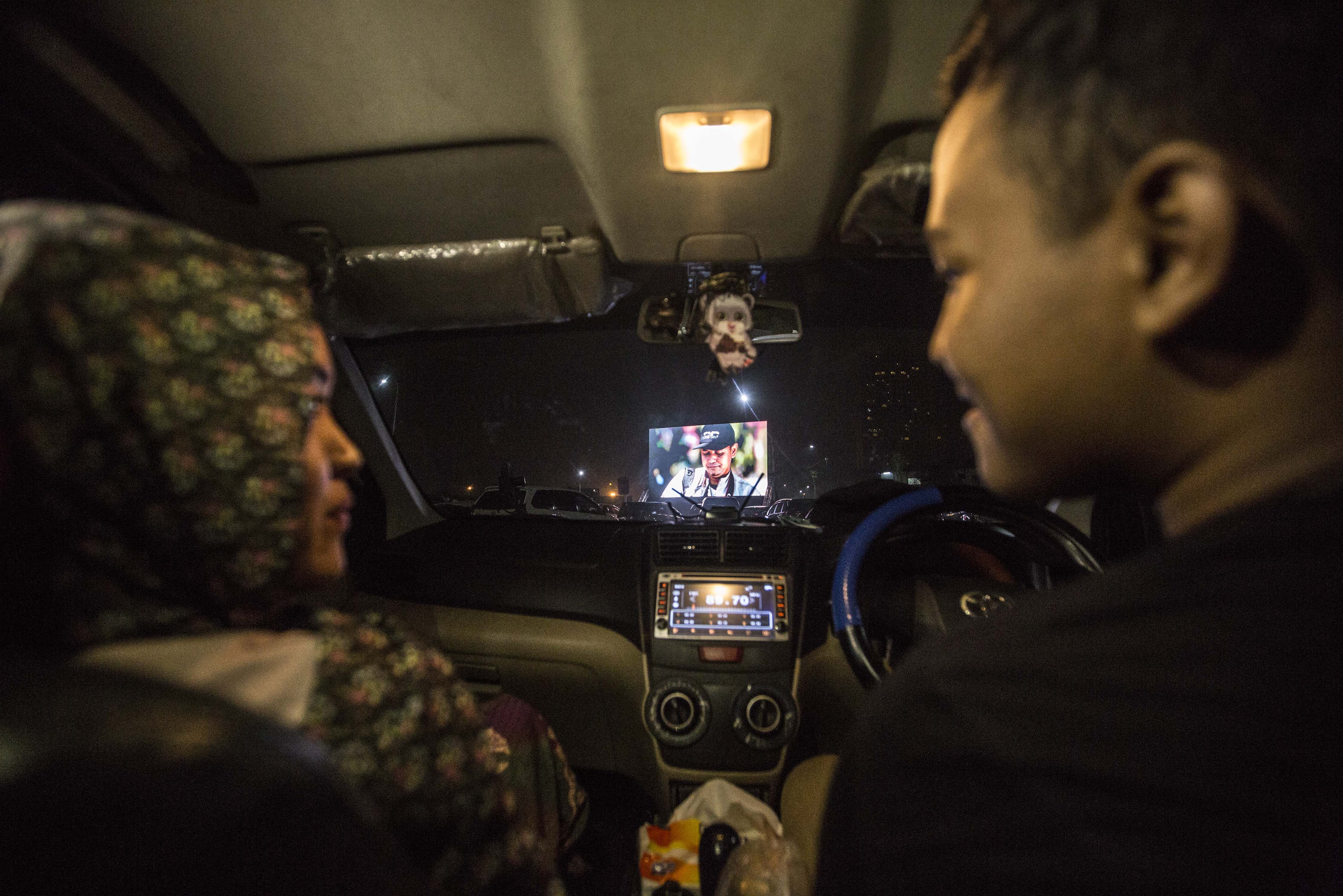Pengunjung menonton film dari dalam mobil di lahan parkir District 1 Meikarta Cikarang, Kabupaten Bekasi, Jawa Barat, Sabtu (6/6/2020). Fasilitas layar lebar disiapkan di lahan parkir untuk pengunjung yang hendak membeli makanan di kawasan District 1 Meikarta secara drive thru dengan menerapkan protokol kesehatan pencegahan Covid-19.