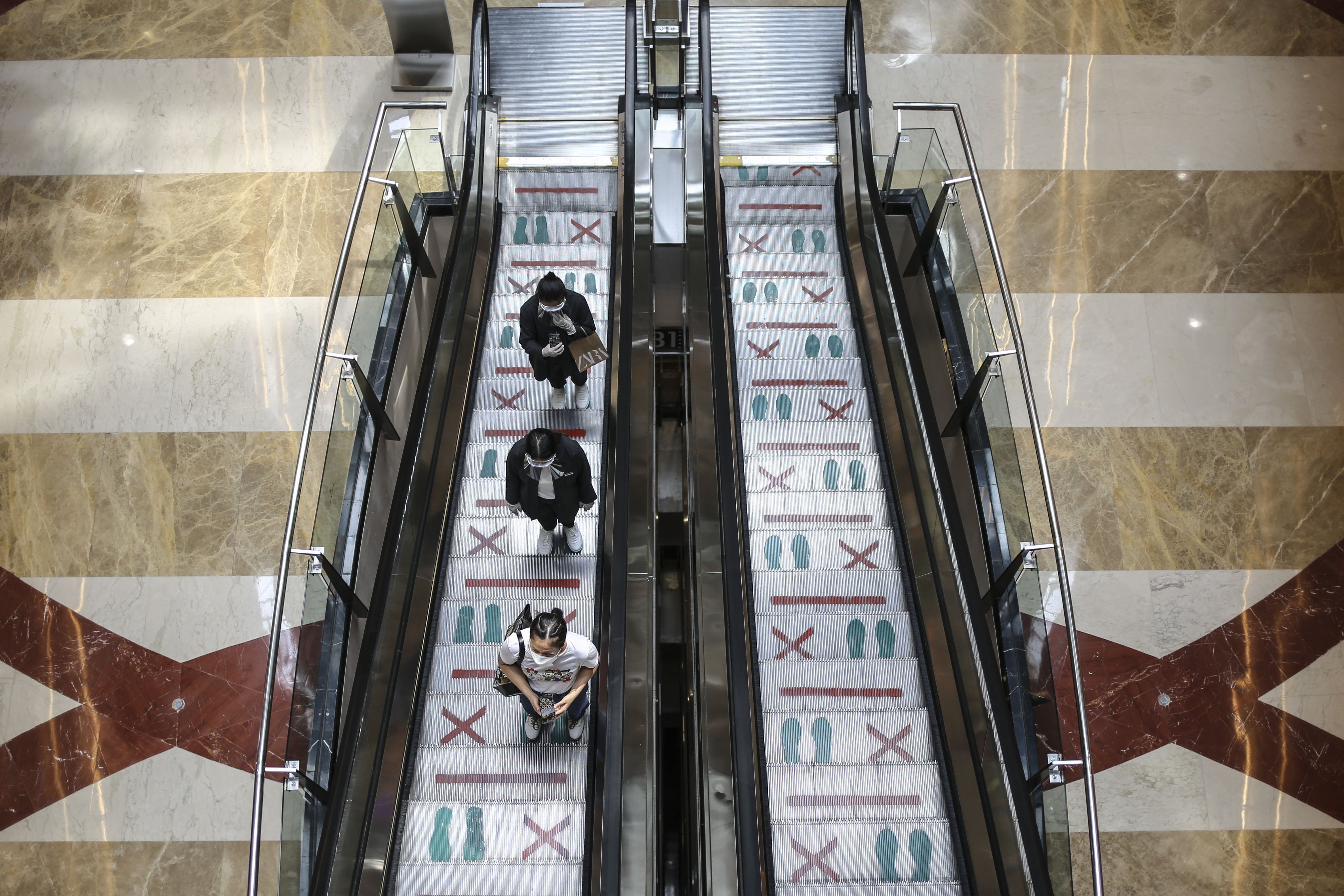 Pengunjung menaiki eskalator dengan berjaga jarak di Pondok Indah Mall, Jakarta.