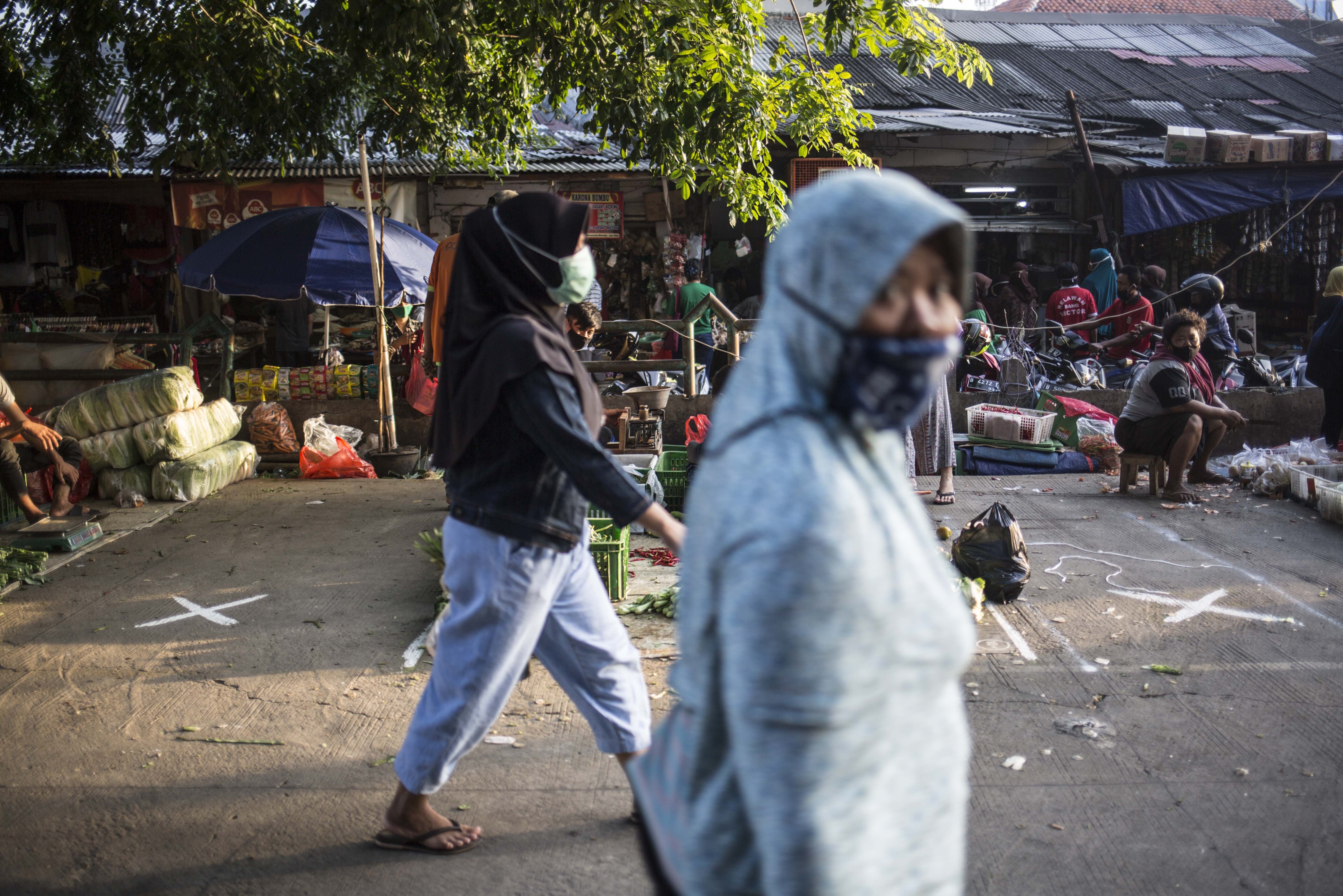 Pedagang berjaga jarak saat berjualan di Pasar Klender, Jakarat.