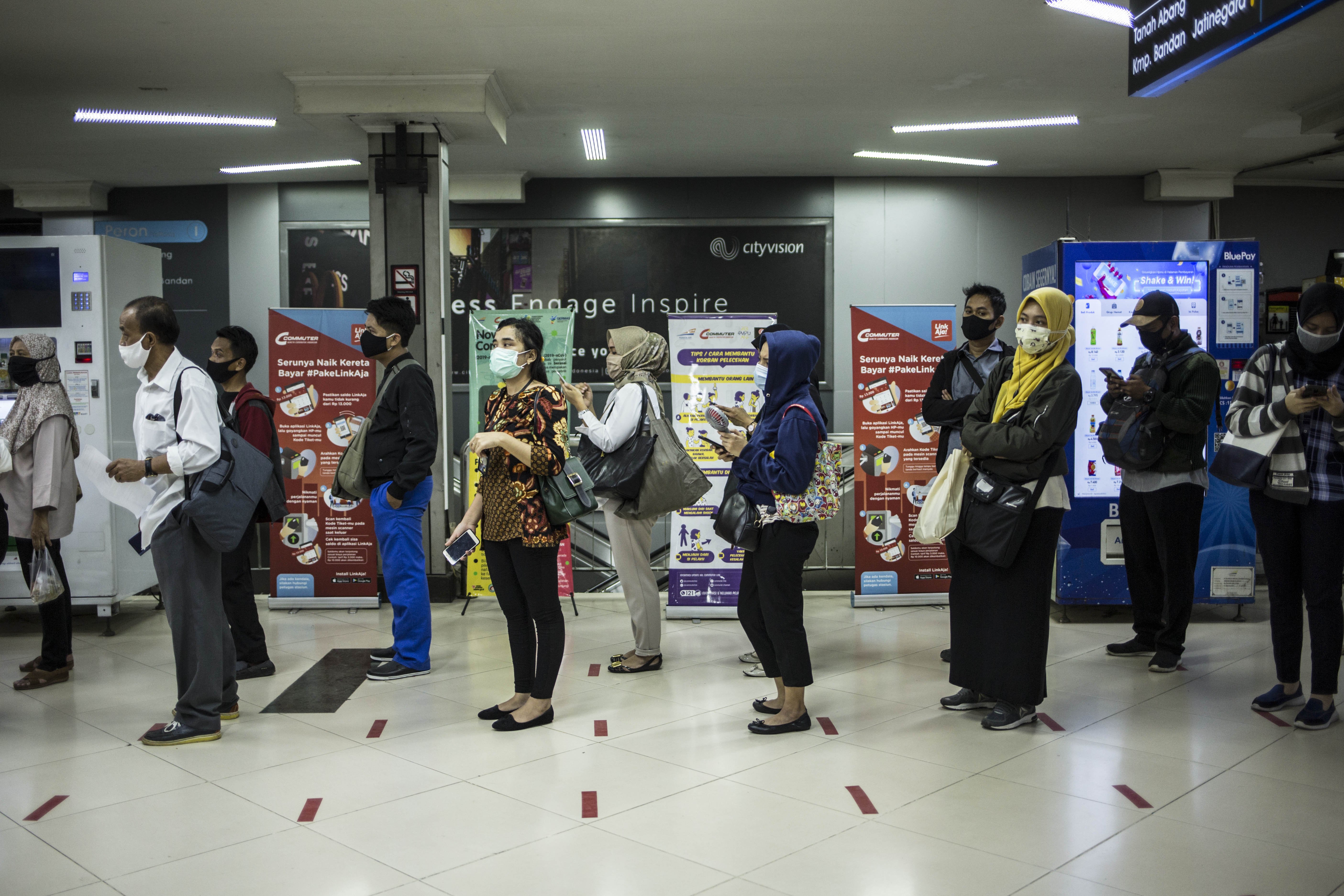 Calon penumpang berjaga jarak saat menunggu KRL di Stasiun Sudirman, Jakarta.