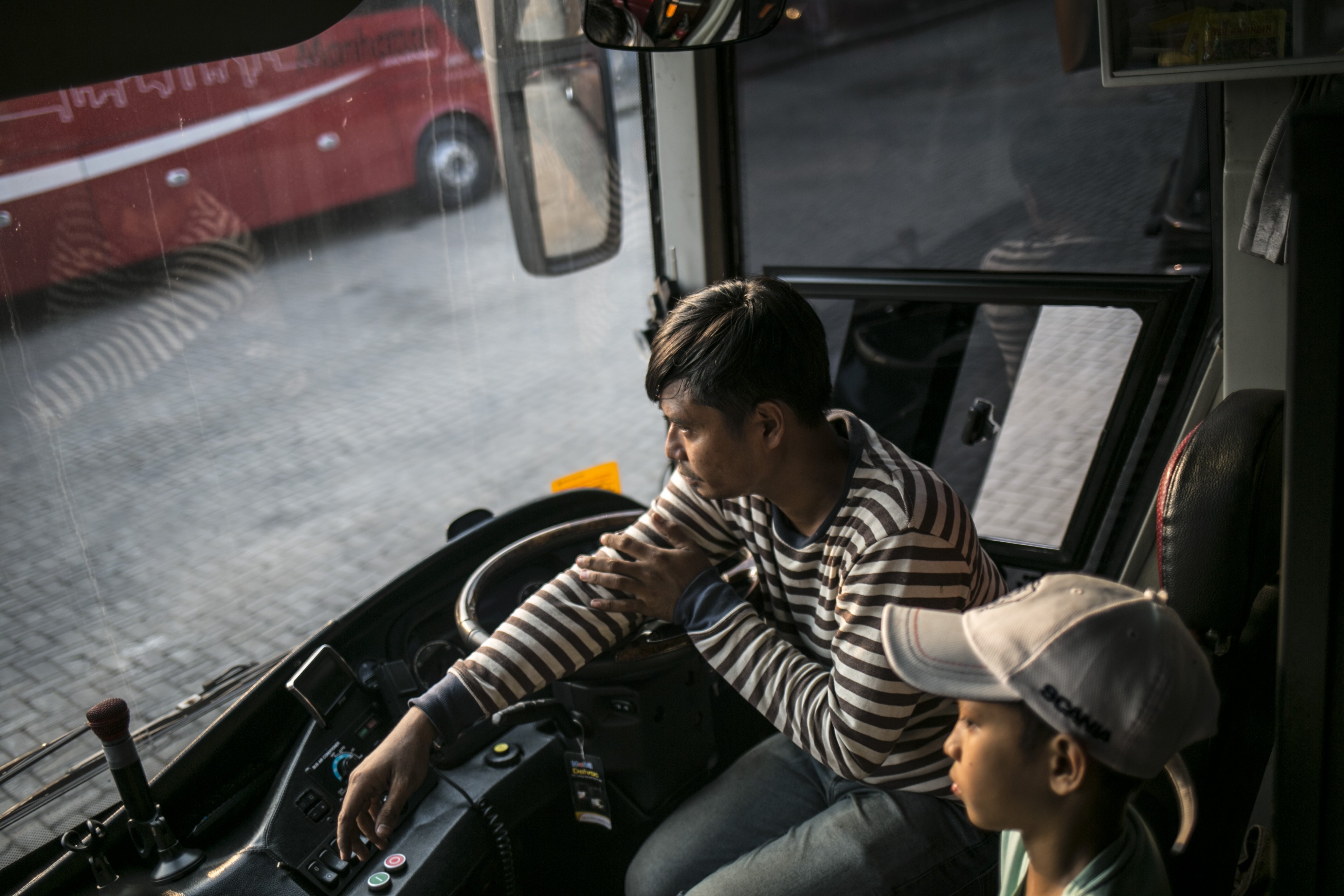 Driver bus, Ade (34) berbincang dengan anaknya di salah satu pool bus pariwisata di kawasan Tanjung Barat, Jagakarsa, Jakarta, Selasa (28/7/2020). Masih diberlakukannya Pembatasan Sosial Bersekala Besar (PSBB) dan penutupan tempat rekreasi akibat Covid-19, berimbas pada jasa transportasi pariwisata. Sejak bulan Maret pengelola mengaku mengalami penurunan pendapatan dan penyewaan bus hingga 80%.