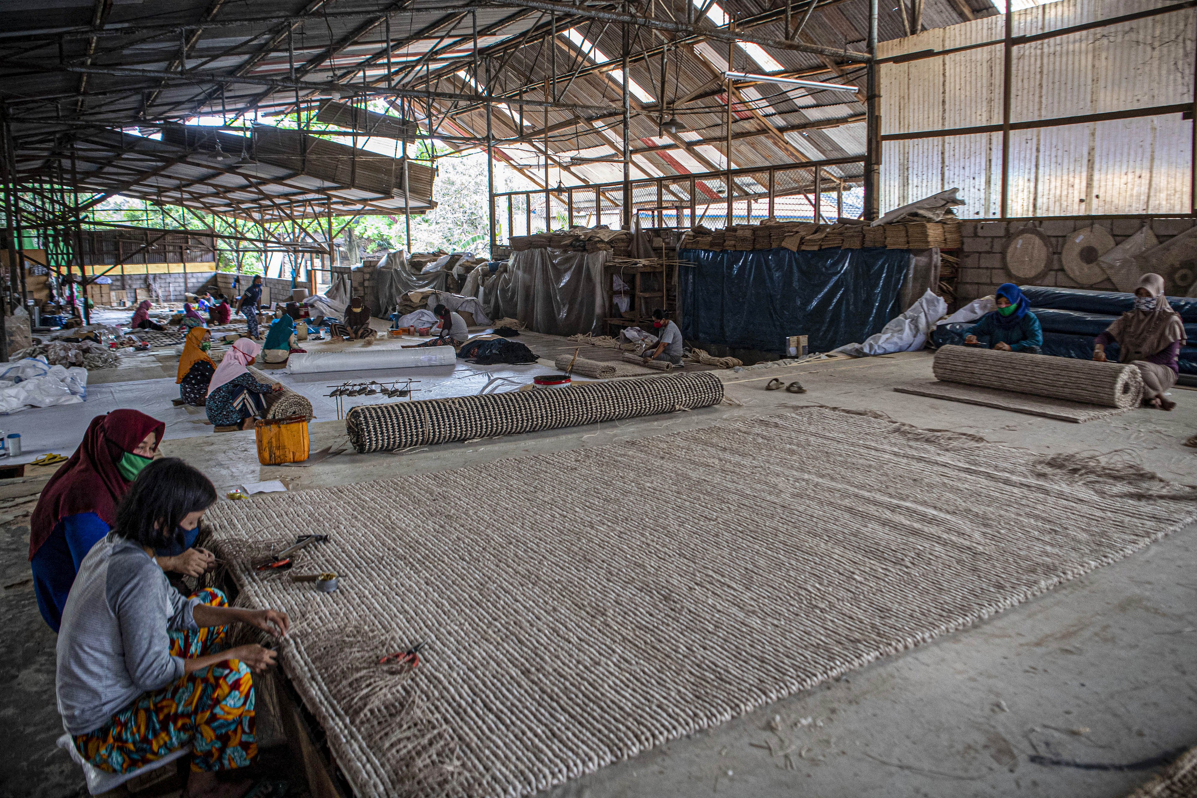 Sejumlah pekerja menganyam pintalan benang dari serat pohon pisang (abaca fiber) untuk dijadikan karpet di bengkel anyam Djunaedi.\r\n