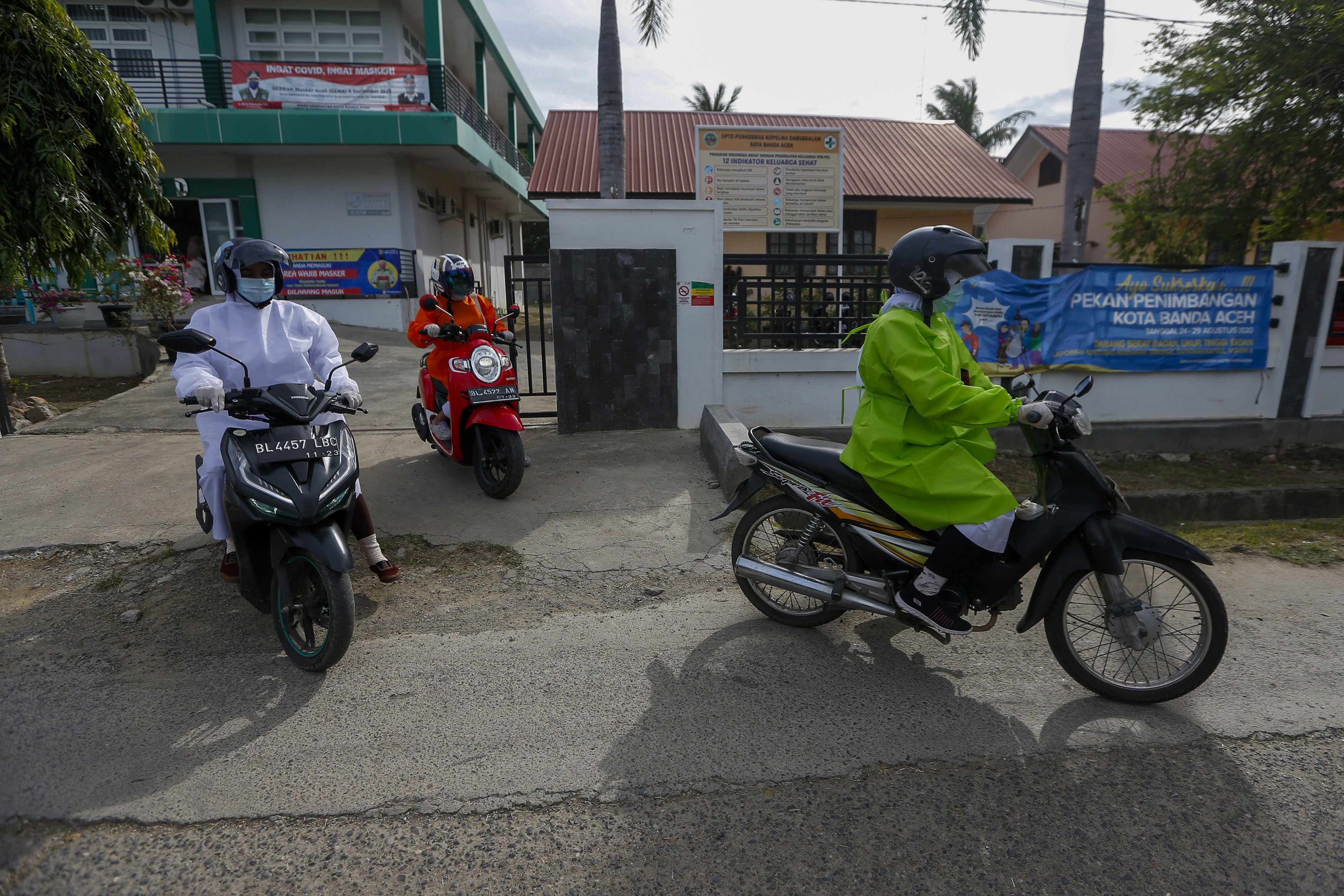 Petugas kesehatan Puskesmas Kopelma Darussalam yang mengenakan alat pelindung diri (APD) guna mencegah penularan COVID-19 menaiki sepeda motor untuk mendatangi para balita yang akan diimunisasi di rumah mereka di Desa Rukoh, Banda Aceh, Aceh, Rabu (7/10/2020). 