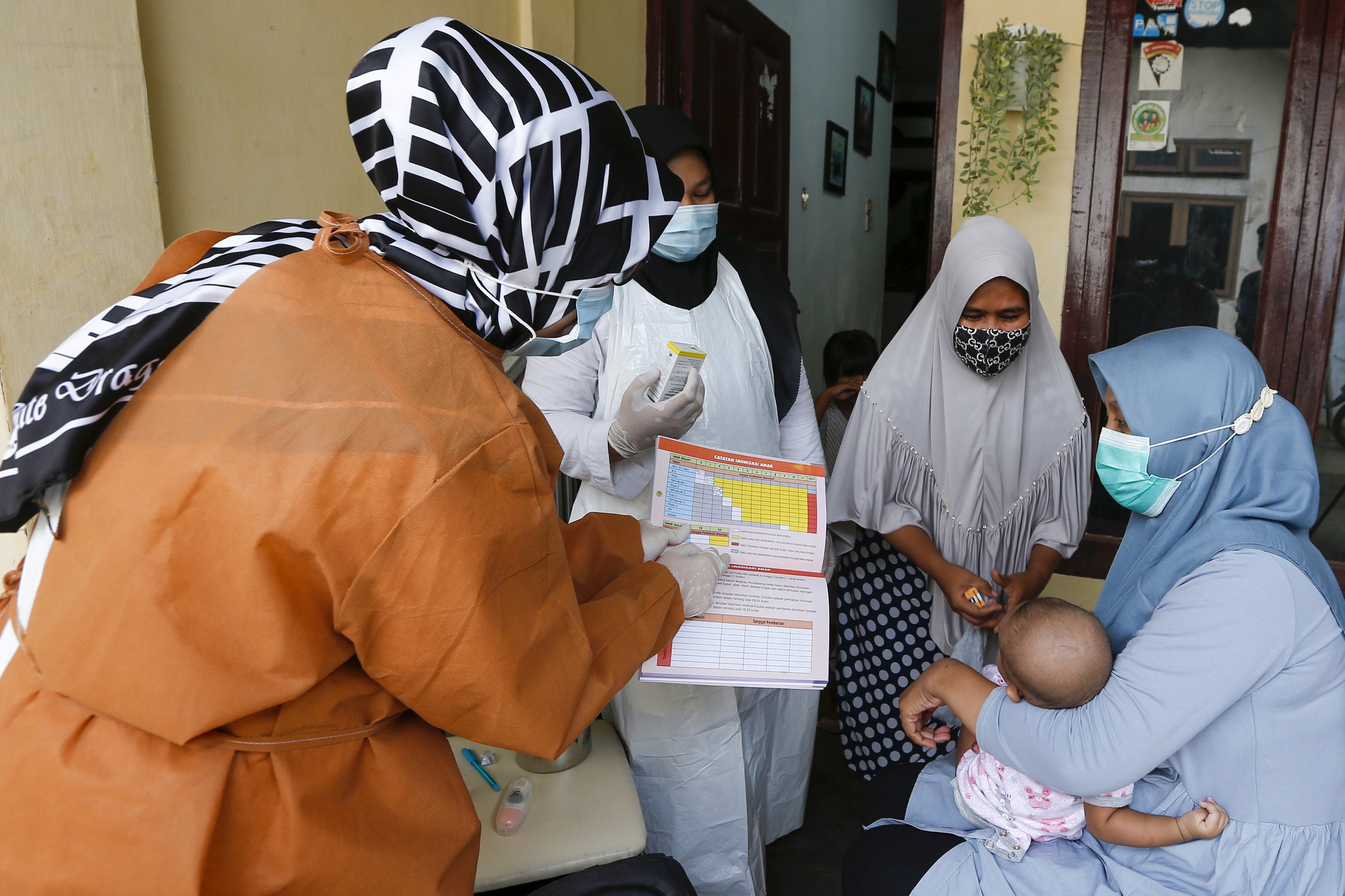 Petugas kesehatan puskesmas (kiri) menjelaskan jadwal dan jenis vaksin imunisasi yang akan diberikan pada balita di rumah mereka di Desa Rukoh, Banda Aceh, Aceh, Rabu (7/10/2020).