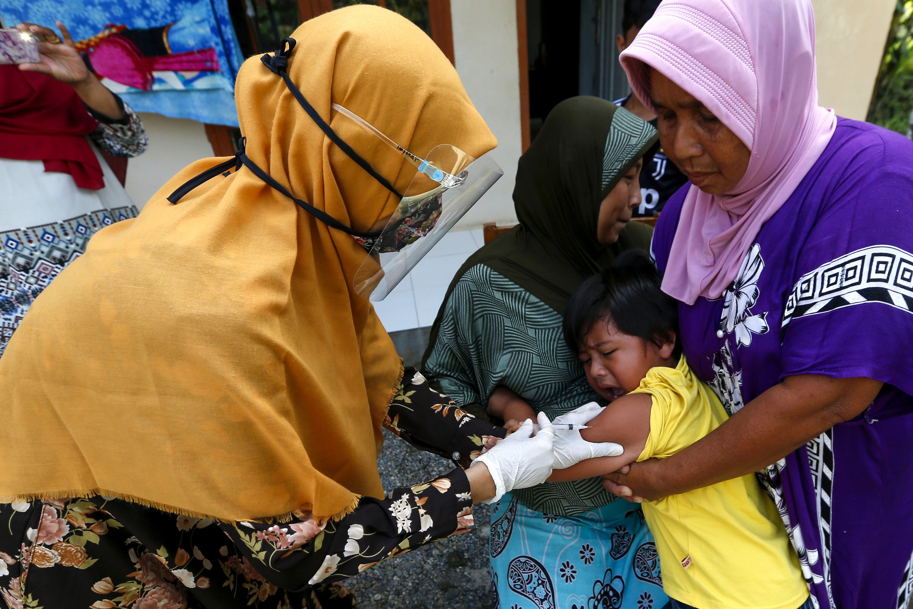 Petugas kesehatan Puskesmas Ulee Kareng (kiri) menyuntikkan vaksin imunisasi kepada balita di rumahnya di Desa Ilie, Banda Aceh, Aceh, Sabtu (5/9/2020). 