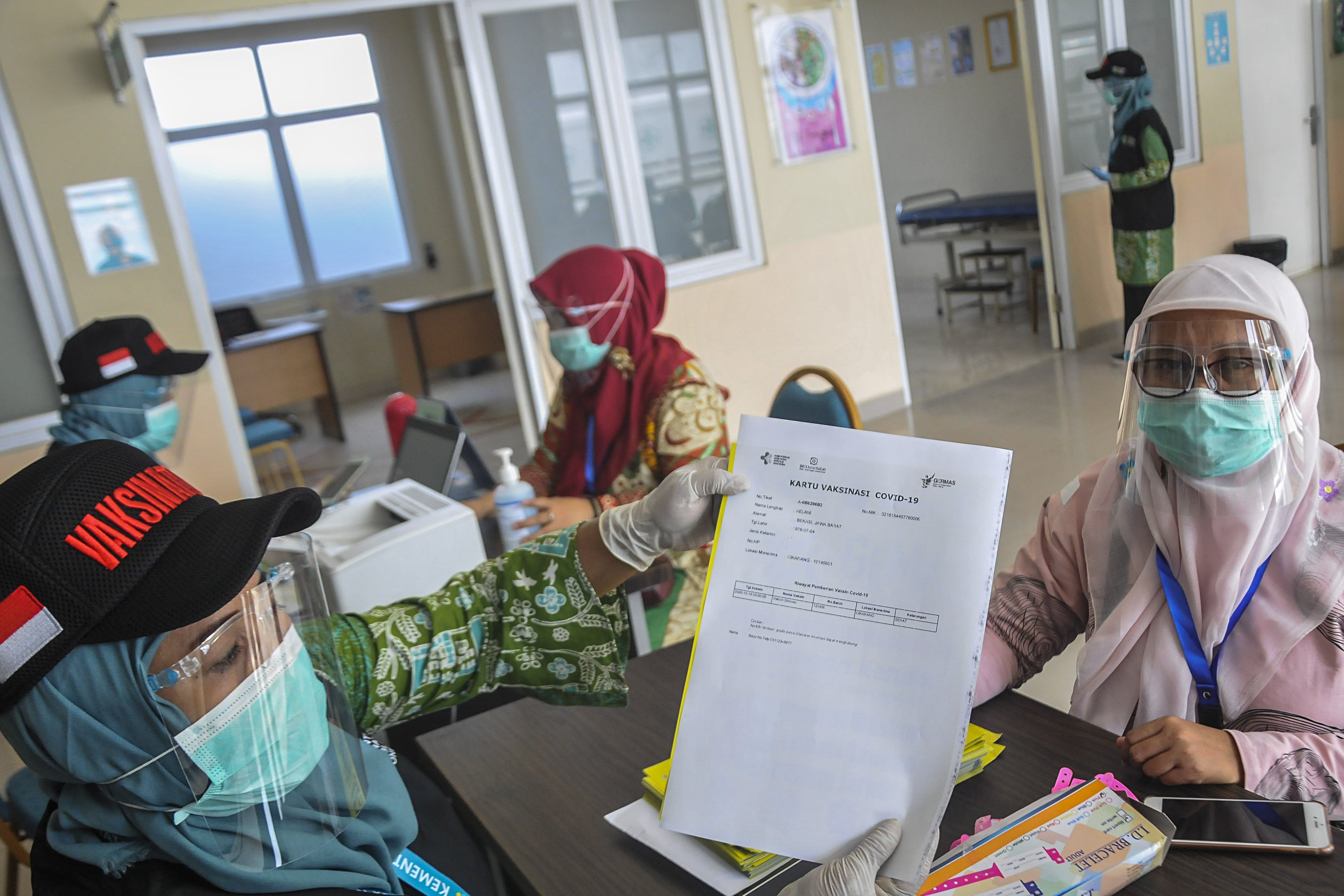 Petugas medis memberikan surat vaksinasi COVID-19 kepada warga saat simulasi di Puskesmas Cikarang, Kabupaten Bekasi, Jawa Barat, Kamis (19/11/2020). Simulasi vaksinasi COVID-19 tersebut merupakan bagian dari upaya pemerintah menyampaikan sosialisasi tentang vaksin COVID-19 yang saat ini masih dalam tahap uji klinis.