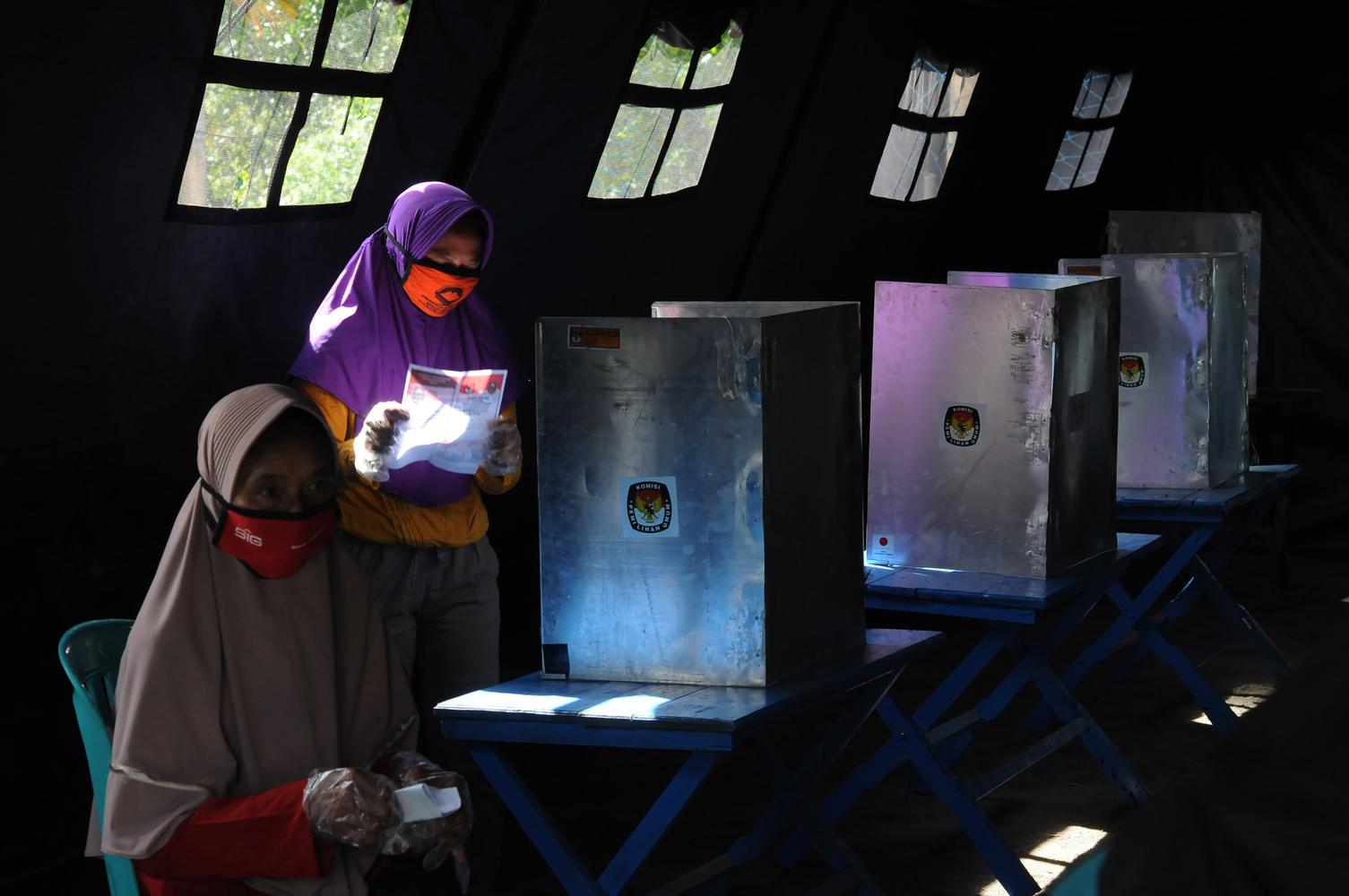 Seorang warga melihat kondisi surat suara saat akan menggunakan hak pilihnya pada Pilkada Kabupaten Boyolali 2020 di tempat pengungsian sementara Gunung Merapi, Tlogolele, Selo, Jawa Tengah, Rabu (9/12/2020).