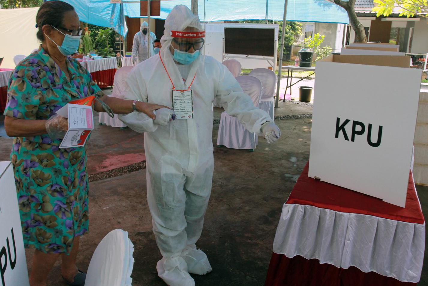 Petugas Kelompok Penyelenggara Pemungutan Suara (KPPS) berpakaian hazmat membantu pemilih menggunakan hak pilihnya di TPS 46 Paku Jaya, Serpong Utara, Tangerang Selatan, Banten, Rabu (9/12/2020). Penggunaan alat pelindung diri (APD) lengkap tersebut untuk meyakinkan masyarakat menggunakan hak pilihnya pada Pilkada Tangerang Selatan 2020 meski di tengah pandemi COVID-19.
