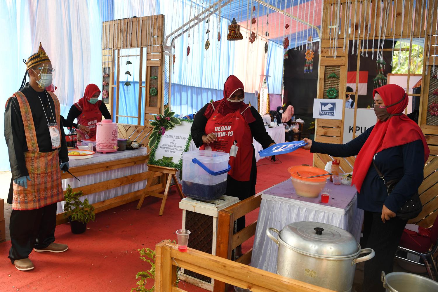 Panitia menyiapkan makanan untuk warga yang menggunakan hak pilihnya pada Pilkada Depok di TPS 31 Benda Barat dengan tema adat Melayu di Depok, Jawa Barat, Rabu (9/12/2020). Pilkada serentak tahun 2020 dilaksanakan di 270 wilayah di Indonesia meliputi sembilan provinsi, 224 kabupaten dan 37 kota dengan menerapkan protokol kesehatan untuk mengantisipasi penyebaran COVID-19.
