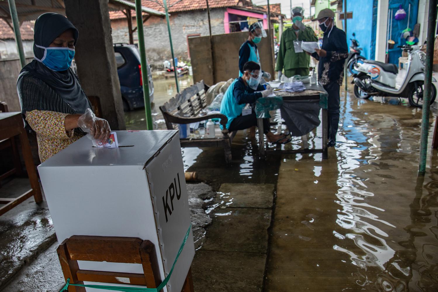 Seorang warga memasukkan surat suara ke dalam kotak suara Pilkada Kabupaten Demak 2020 di TPS 12 yang tergenang air rob di Desa Tridonorejo, Bonang, Demak, Jawa Tengah, Rabu (9/12/2020). Sejumlah TPS di pesisir setempat tergenang air rob dengan ketinggian bervariasi antara 10-30 sentimeter.