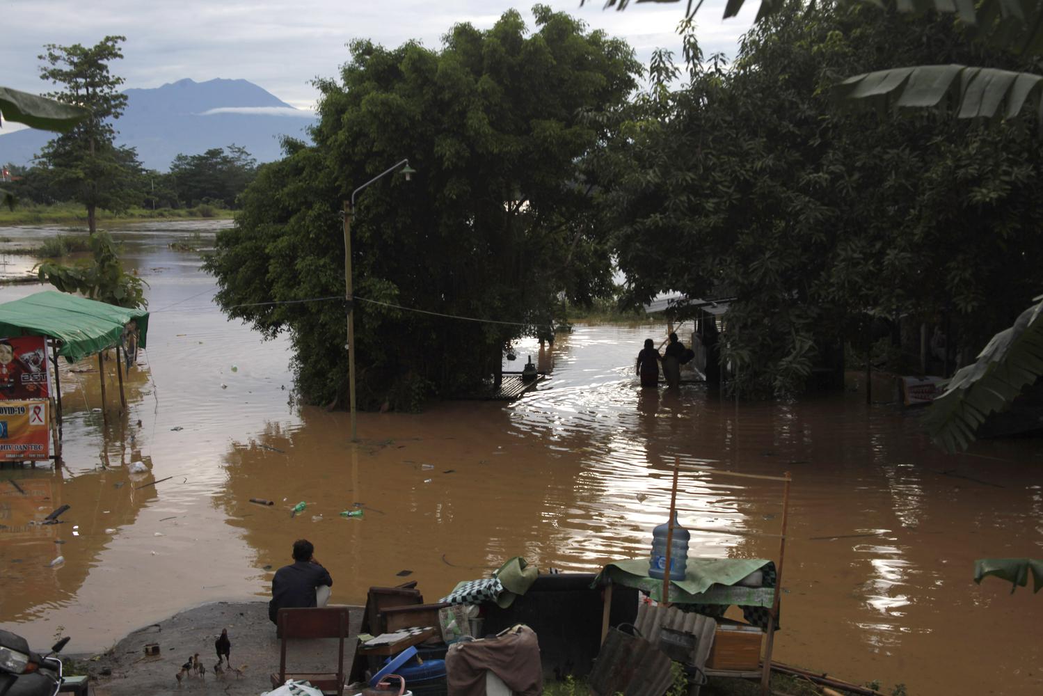 Warga duduk di tempat yang lebih tinggi saat banjir menggenangi permukiman di Kampung Sewu, Jebres, Solo, Jawa Tengah, Senin (14/12/2020). Puluhan keluarga yang tinggal di sekitar bantaran sungai setempat terdampak luapan air Sungai Bengawan Solo.