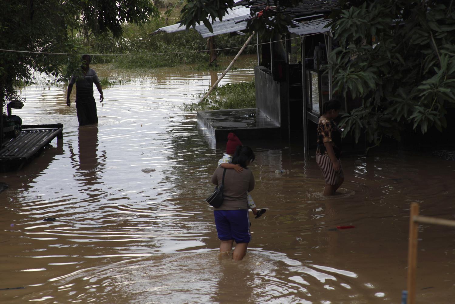 Warga berjalan melintasi banjir yang menggenangi permukiman di Kampung Sewu, Jebres, Solo, Jawa Tengah, Senin (14/12/2020). Puluhan keluarga yang tinggal di sekitar bantaran sungai setempat terdampak luapan air Sungai Bengawan Solo.