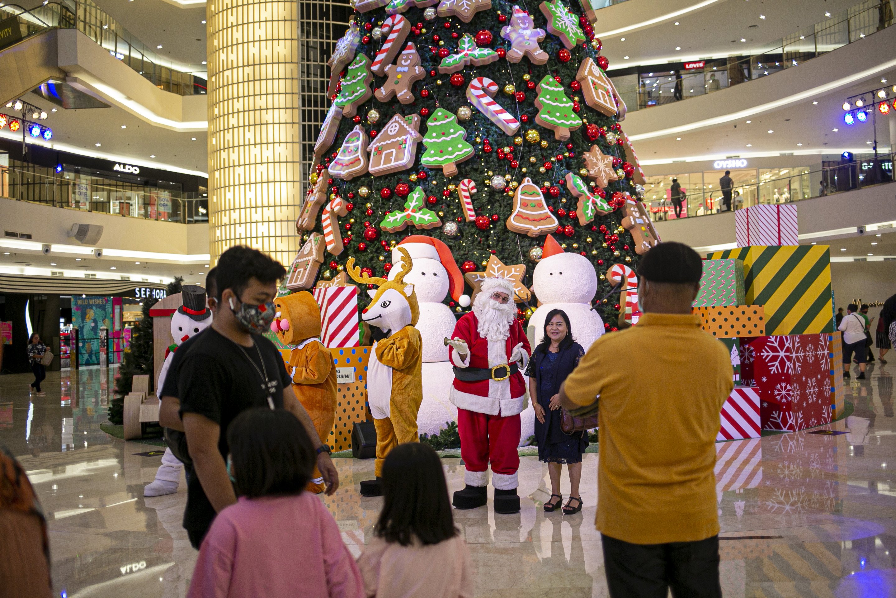 Pengunjung berfoto dengan latar belakang pohon Natal di Mall Senayan City, Jakarta, Minggu (20/12/2020). Jelang Natal 2020 sejumlah pusat perbelanjaan di Ibu kota menghias ruang pertokoan dengan ornamen Natal.