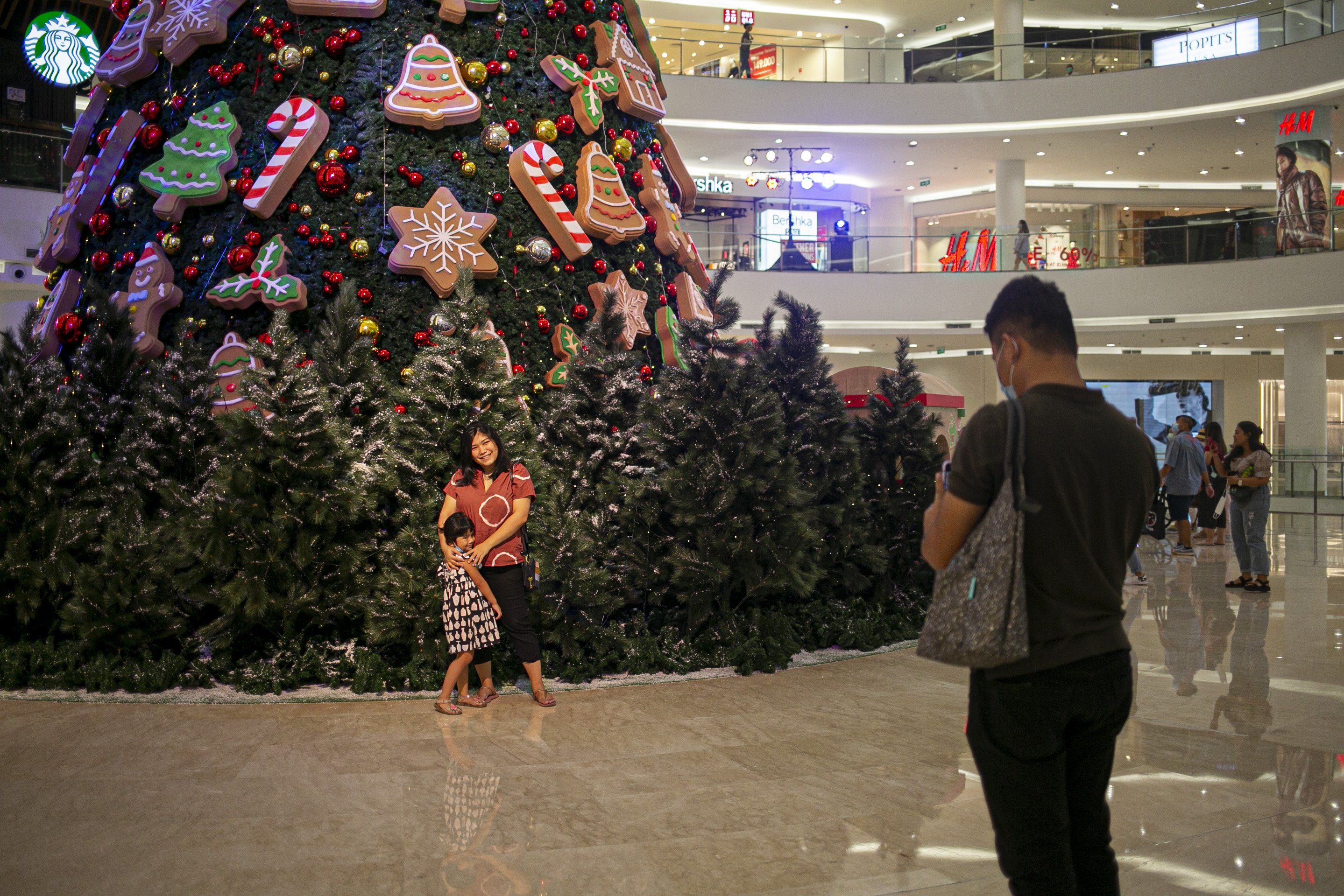 Pengunjung berfoto dengan latar belakang pohon Natal di Mall Senayan City, Jakarta, Minggu (20/12/2020). Jelang Natal 2020 sejumlah pusat perbelanjaan di Ibu kota menghias ruang pertokoan dengan ornamen Natal.