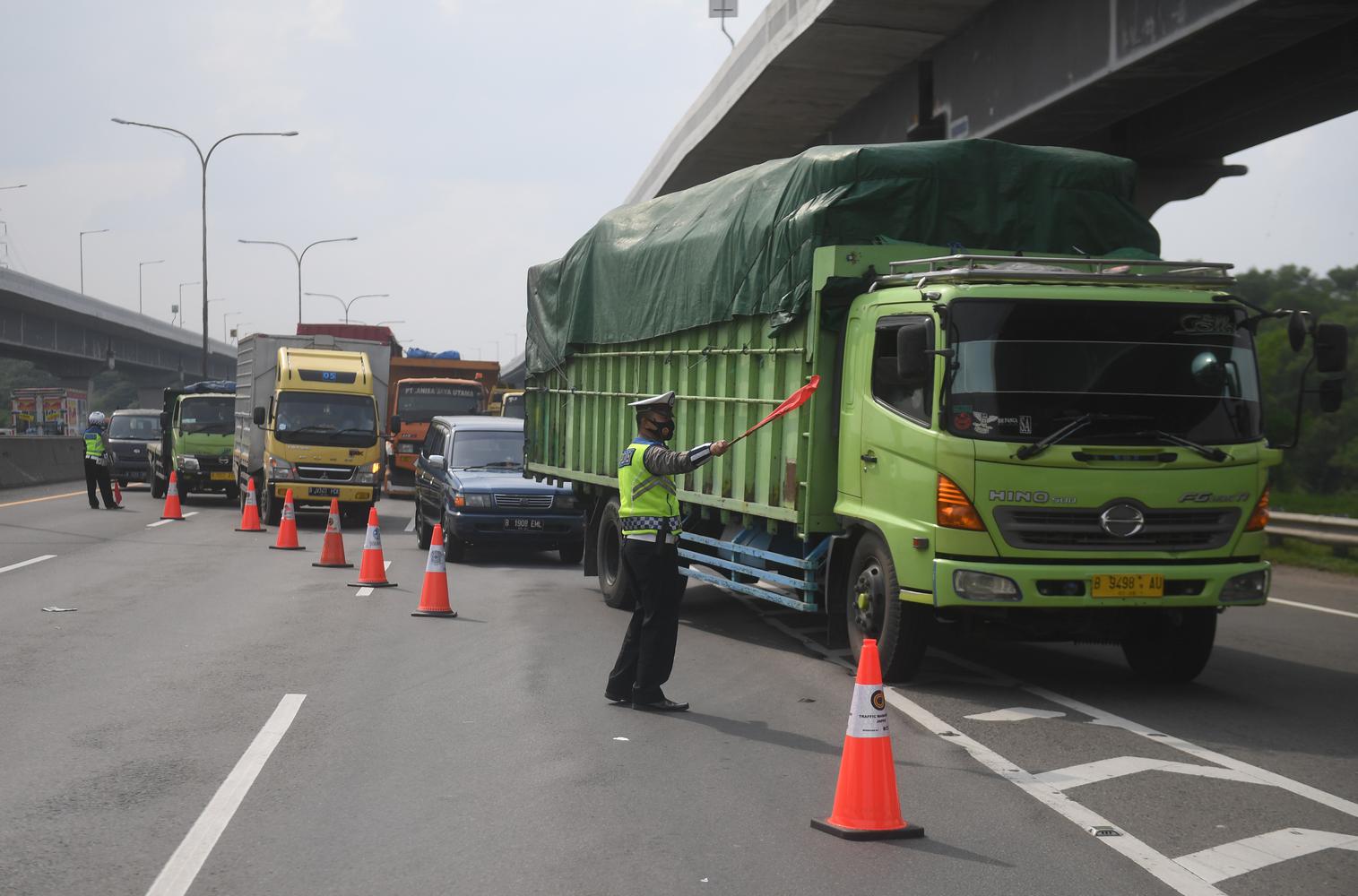 Polisi mengarahkan angkutan barang untuk keluar dari Tol Jakarta-Cikampek melalui pintu tol Karawang Barat di Karawang, Jawa Barat, Rabu (23/12/2020). Pengalihan angkutan barang tersebut dilakukan untuk menjaga kelancaran arus mudik Natal dan tahun baru.
