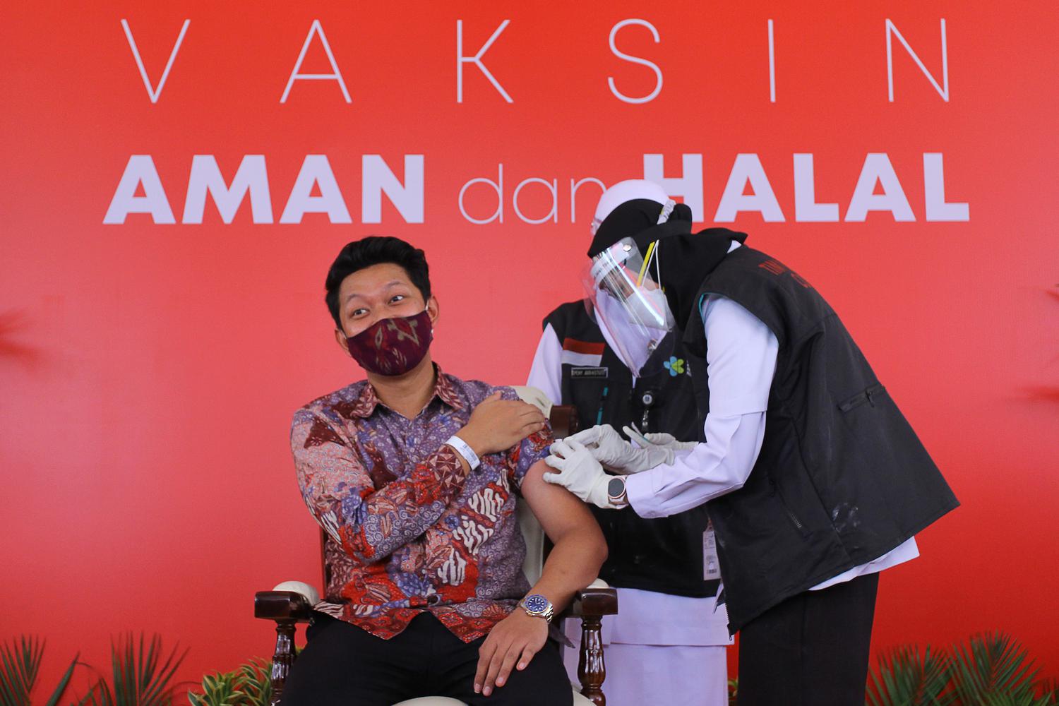 Tenaga kesehatan menyuntikkan vaksin Sinovac kepada perwakilan pemuda sekalligus aktor Bayu Eko Muktito (Bayu Skak) saat vaksinasi COVID-19 di Gedung Negara Grahadi, Surabaya, Jawa Timur, Kamis (14/1/2021). Vaksinasi perdana kepada 21 orang perwakilan tersebut menandai dimulainya program vaksinasi COVID-19 di sejumlah daerah di Jawa Timur.