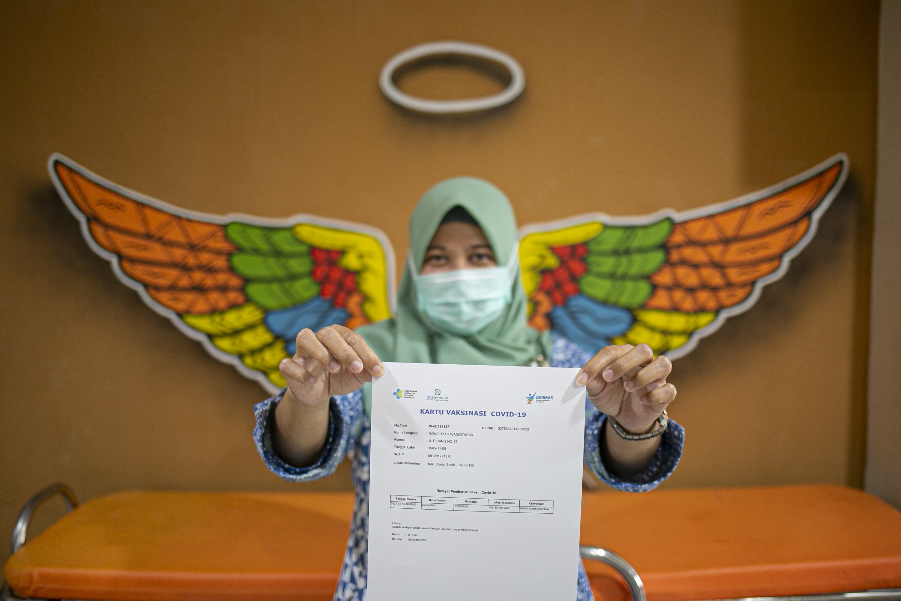 Tenaga kesehatan menunjukkan kartu vaksinasi COVID-19 seusai disuntik CoronaVac di Puskesmas Duren Sawit, Jakarta Timur, (14/1/2021). Program vaksinasi COVID-19 tahap pertama kepada tenaga kesehatan mulai dilakukan di berbagai daerah di Indonesia.