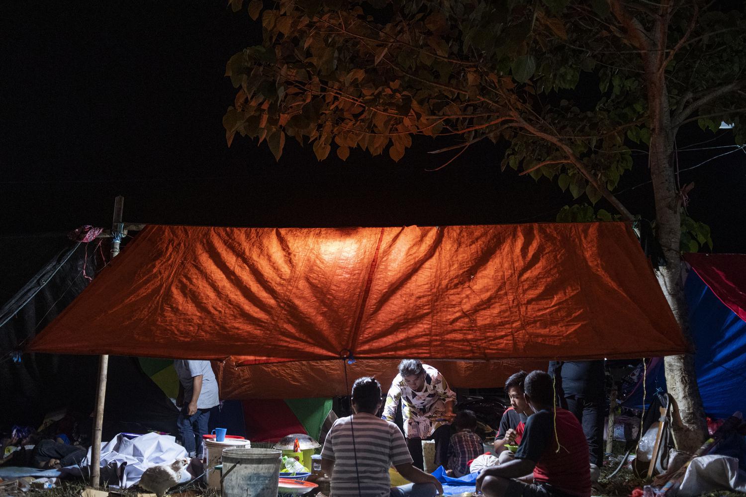 Sejumlah pengungsi korban gempa makan malam di tenda darurat yang mereka buat di kompleks Stadion Manakarra, Mamuju, Sulawesi Barat, Minggu (17/1/2021). BNPB menyatakan berdasarkan data per 17 Januari pukul 14.00 WIB jumlah korban gempa bumi Sulawesi Barat yang meninggal berjumlah 73 orang dan sebanyak 27.850 orang mengungsi di 25 titik pengungsian.