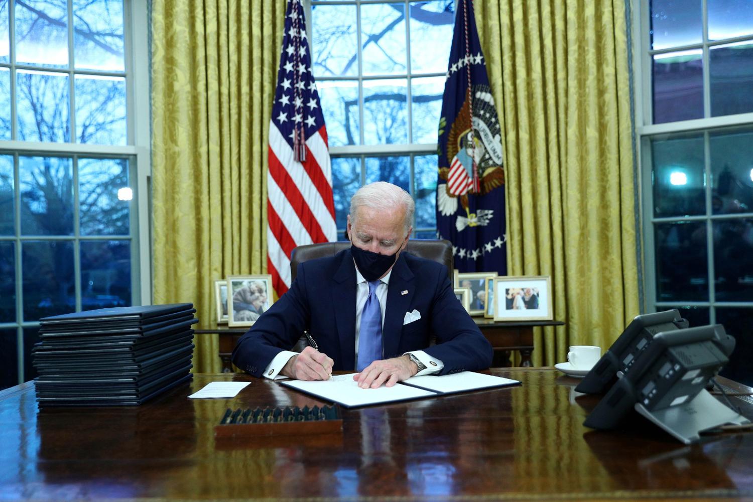 Tom Brenner Presiden Amerika Serikat Joe Biden menandatangani perintah eksekutif di Ruang Oval Gedung Putih setelah pelantikannya sebagai Presiden Amerika Serikat ke-46, di Washington, Amerika Serikat, Rabu (20/1/2021).