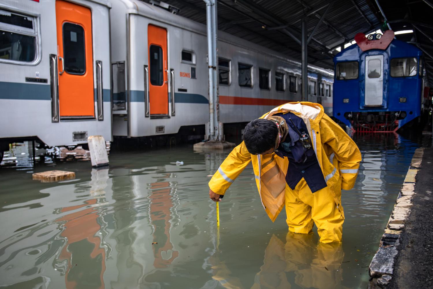 Karyawan mengukur ketinggian banjir pada lintasan kereta api di Stasiun Tawang, Semarang, Jawa Tengah, Sabtu (6/2/2021). Akibat banjir setinggi hingga 70 cm tersebut, PT KAI (Persero) DAOP 4 Semarang mengalihkan sejumlah rute perjalanan kereta api.