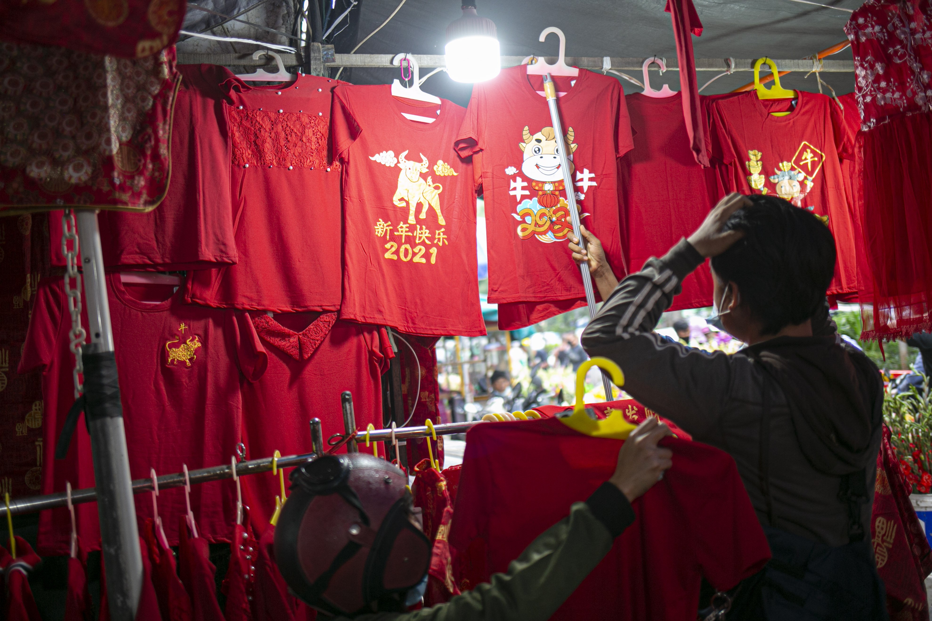 Calon pembeli memilih baju Imlek yang dijual di Pasar Glodok, Jakarta, Kamis (11/2/2021). Pedagang di lokasi tersebut mengaku penjualan tahun ini anjlok hingga 80 persen dibandingkan tahun lalu akibat pandemi COVID 19.