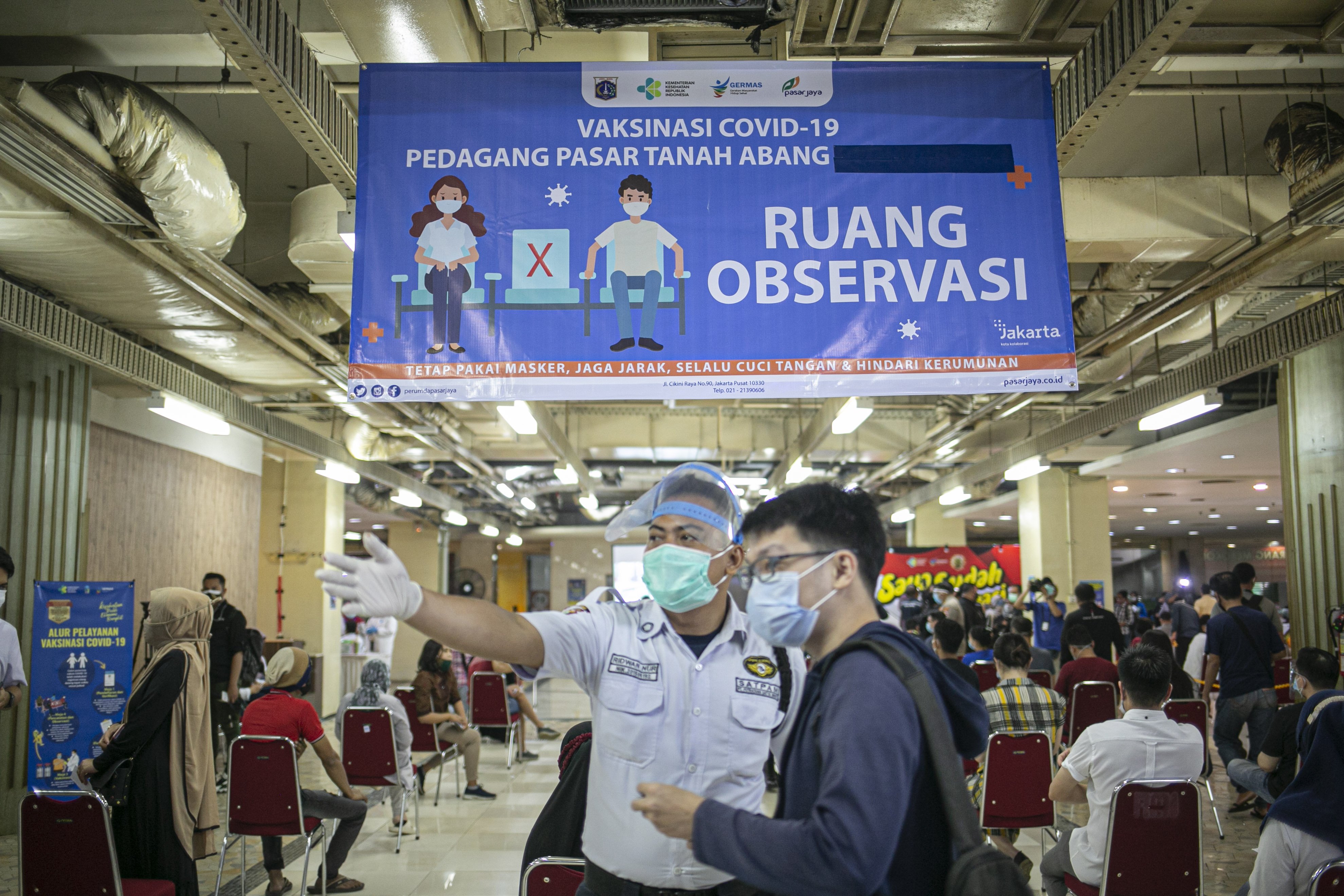 Petugas keamanan mengarahkan pedagang saat proses vaksinasi di Pasar Tanah Abang Blok A, Jakarta, Rabu (17/2/2021). Vaksinasi covid-19 tahap kedua yang diberikan untuk pekerja publik dan lansia itu dimulai dari pedagang Pasar Tanah Abang.