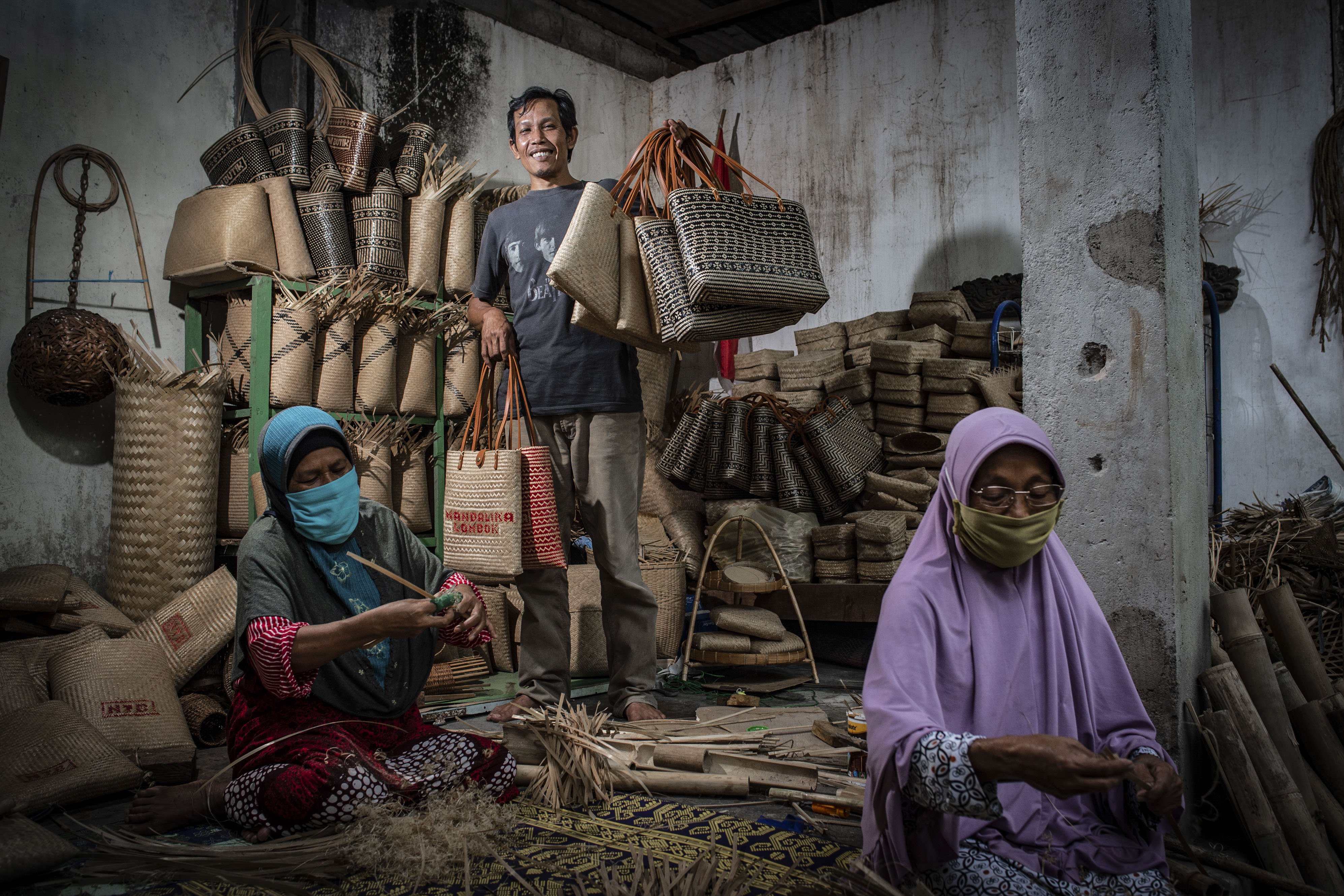 Agus Hartadi (tengah) berpose dengan memegang tas hasil kerajinannya di Desa Loyok, Sakra, Lombok Timur, Nusa Tenggara Barat.