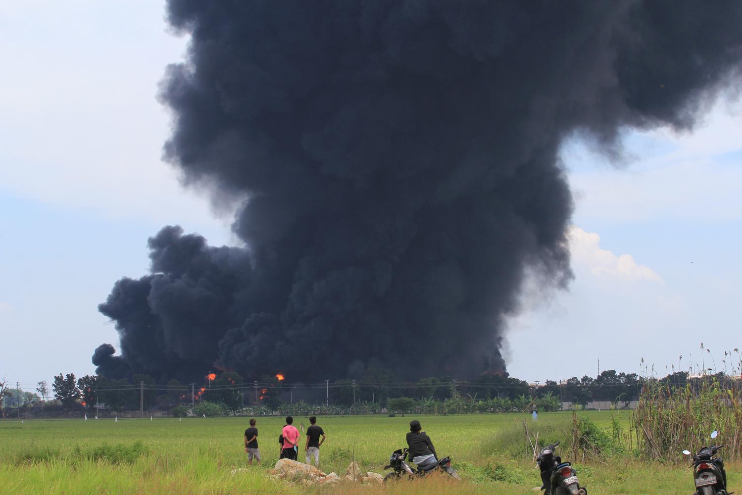 Warga melihat kepulan asap hitam akibat kebakaran tangki minyak milik Pertamina RU VI Balongan, Indramayu, Jawa Barat, Senin (29/3/2021). Akibat kebakaran tersebut sedikitnya 20 orang terluka dan 500 warga yang tinggal di dekat lokasi terpaksa mengungsi.