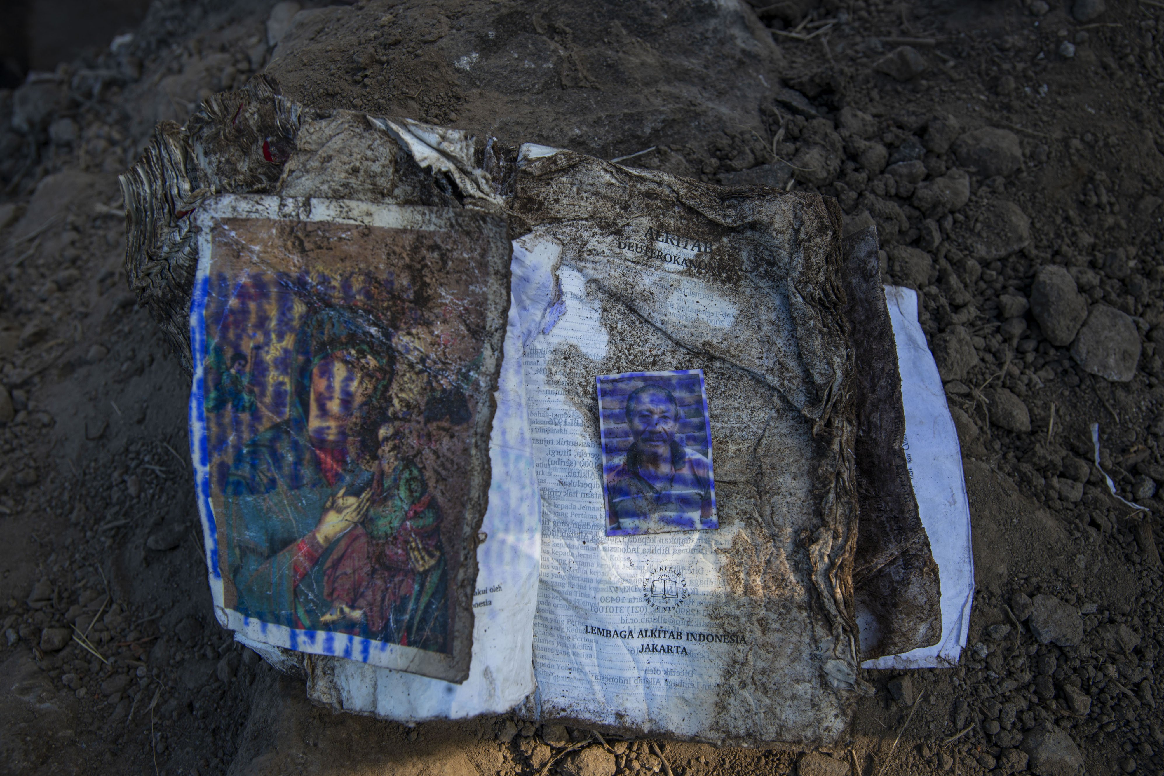 Sebuah kitab suci Alkitab bersama foto pemiliknya berada di antara puing-puing reruntuhan akibat tanah longsor di Desa Waematan, Ile Ape, Kabupaten Lembata, Nusa Tenggara Timur (NTT).