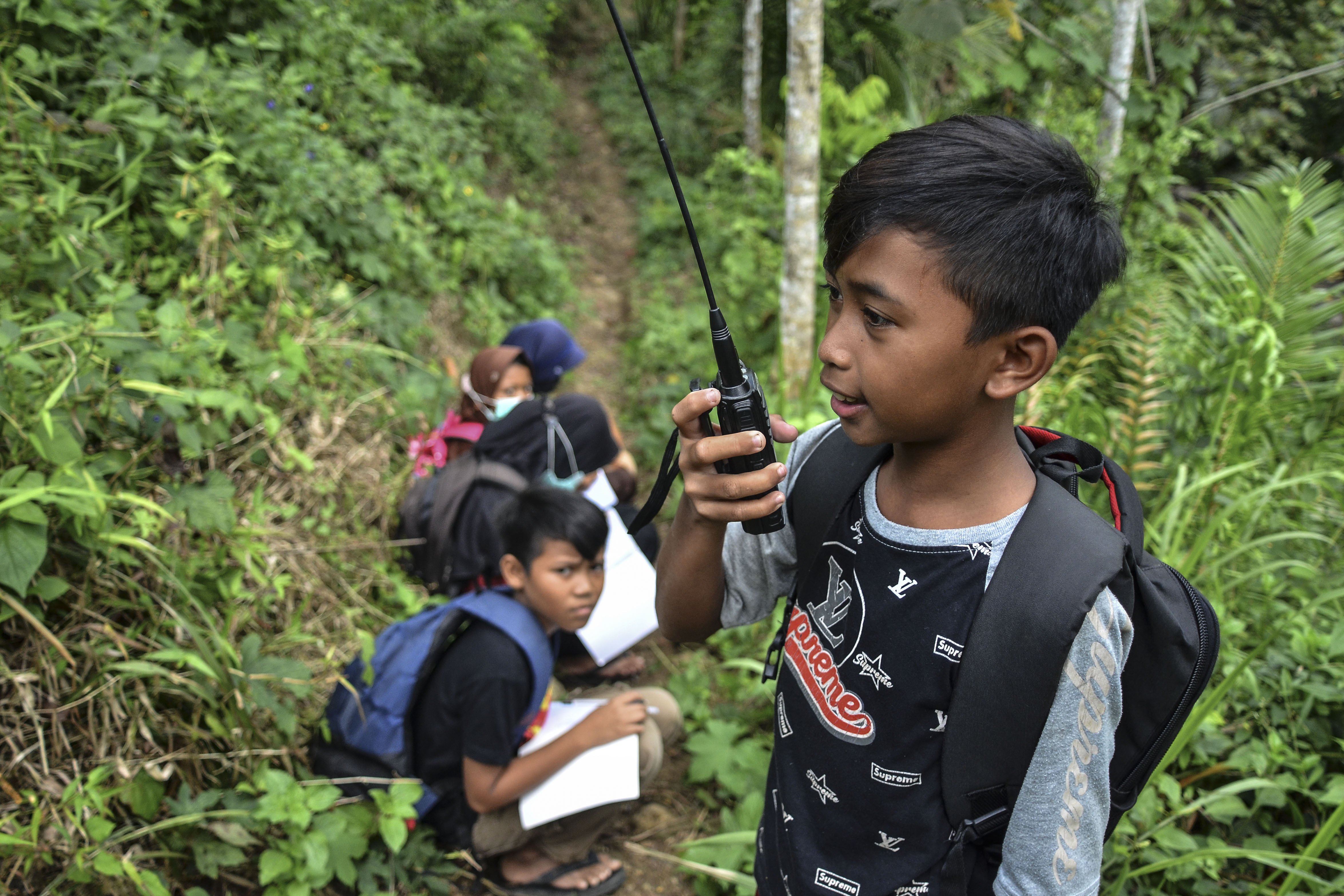 Siswa sekolah Madrasah Ibtidaiyah Pasawahan menggunakan radio Handy Talky (HT) saat pembelajaran jarak jauh di kawasan hutan, Dusun Ciakar, Desa Pasawahan, Kecamatan Banjaranyar Kabupaten Ciamis, Jawa Barat.