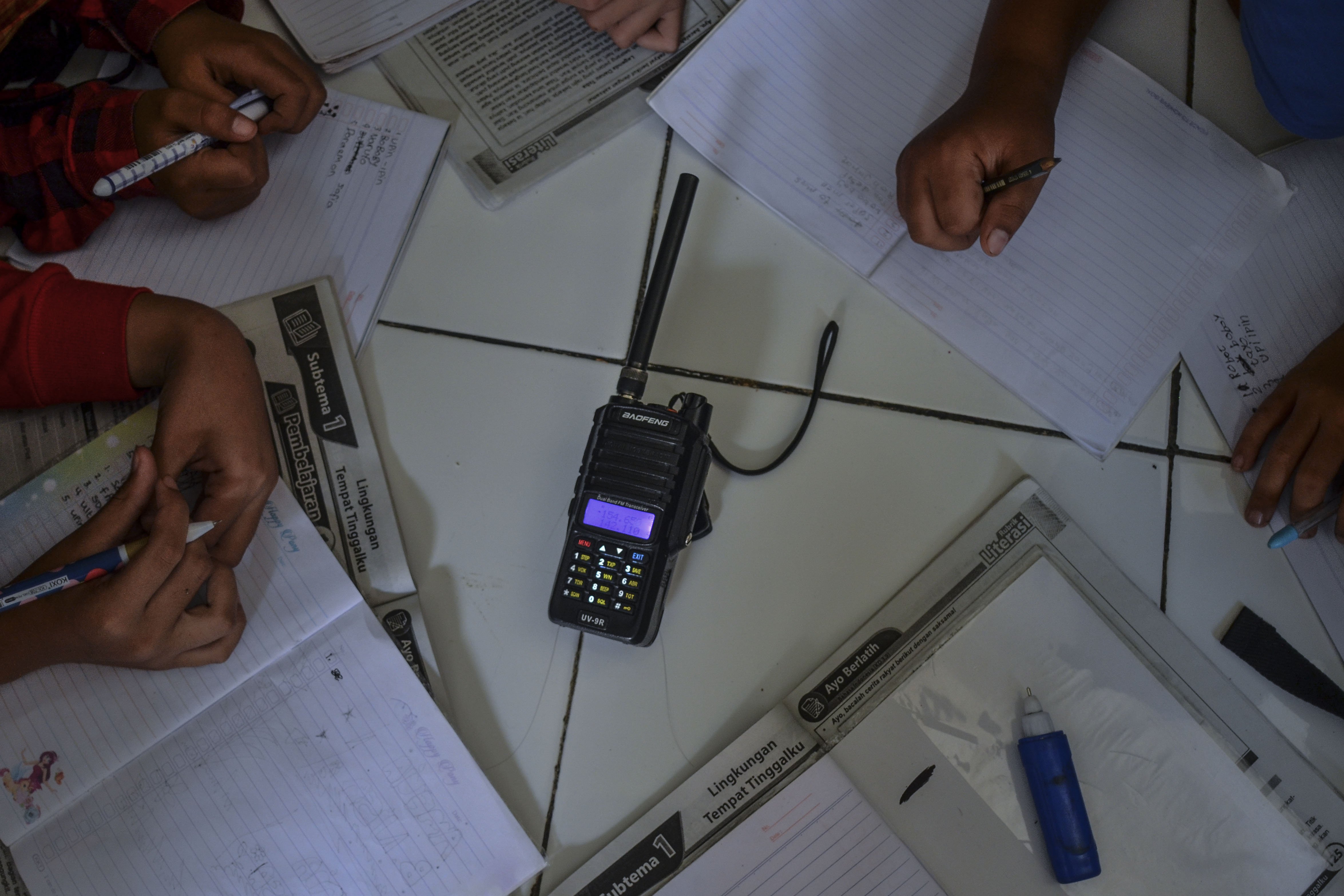 Siswa sekolah Madrasah Ibtidaiyah Pesawahan mendengarkan arahan wali kelas dari radio Handy Talky (HT) saat pembelajaran jarak jauh secara kelompok di Rumah Dusun Ciakar, Desa Pasawahan, Kecamatan Banjaranyar Kabupaten Ciamis, Jawa Barat.