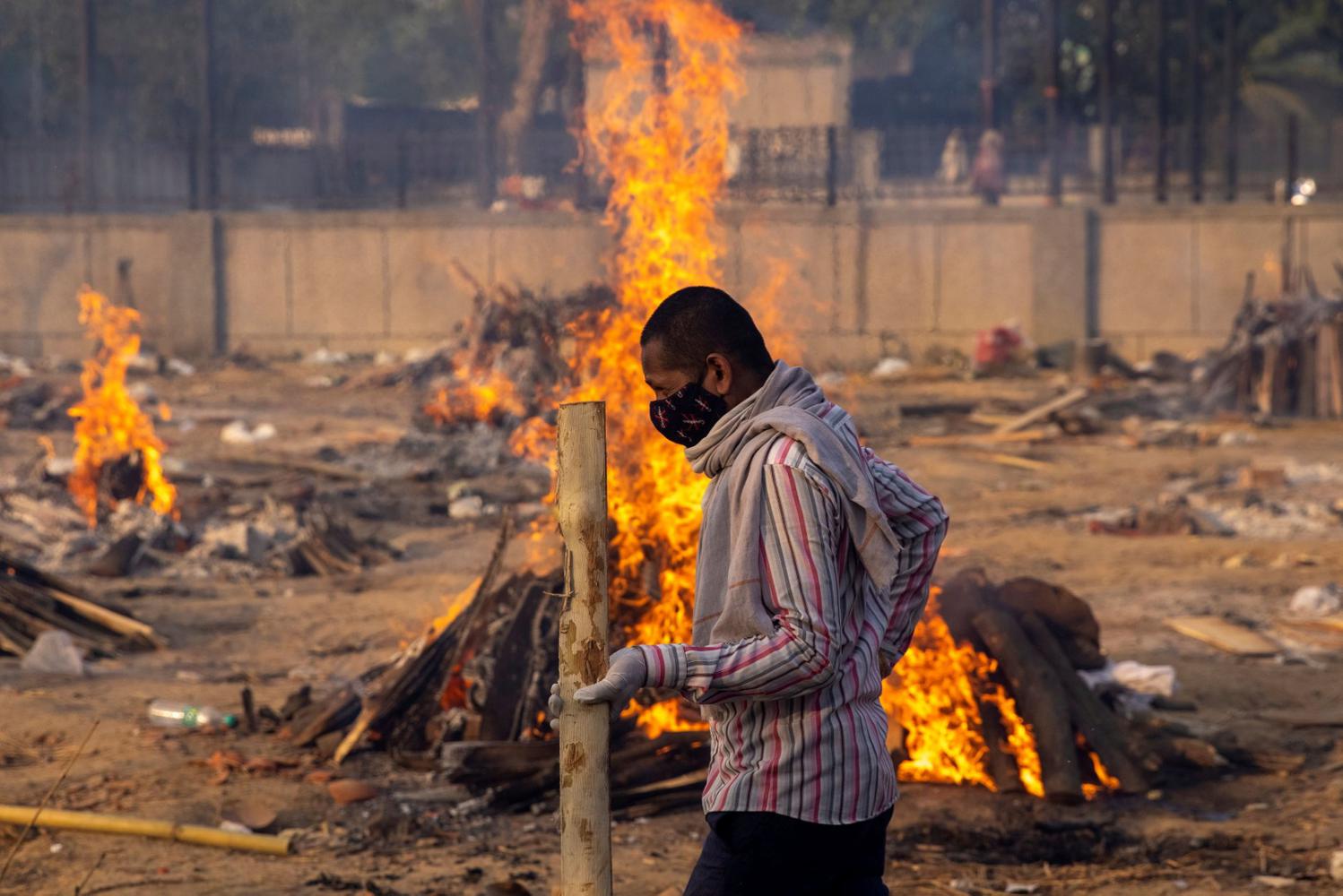 Danish Siddiqui 

 Seorang pria berjalan melewati pembakaran tumpukan kayu pemakaman orang, yang meninggal karena penyakit virus corona (COVID-19), di tempat krematorium di New Delhi, India, Kamis (22/4/2021).