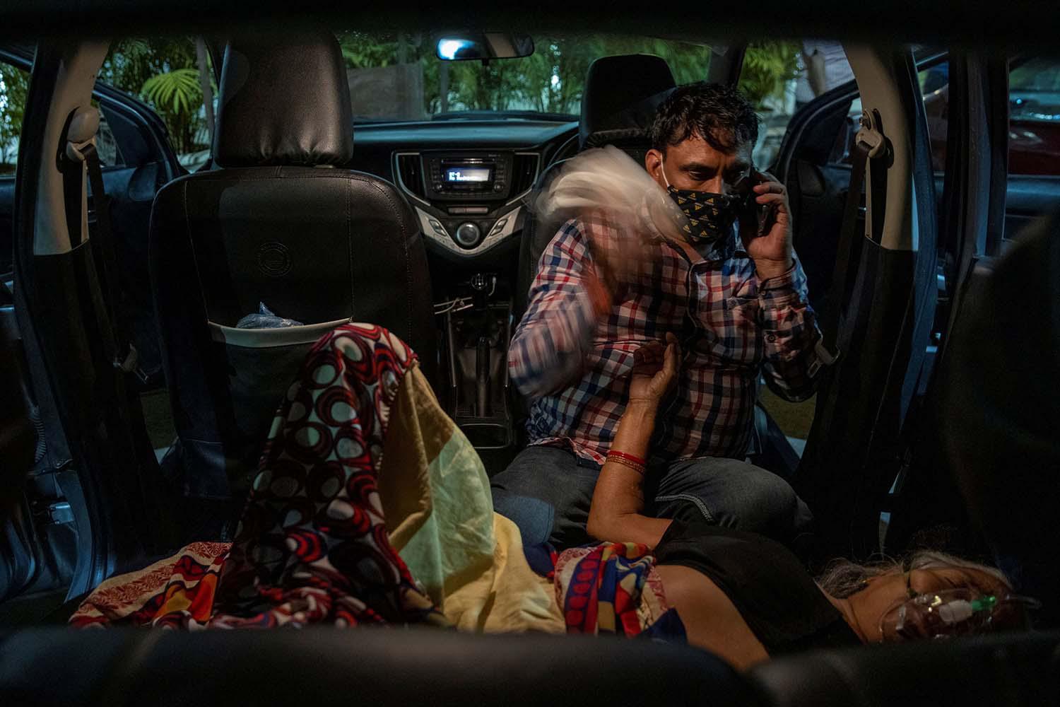 Danish Siddiqui Manoj Kumar duduk di sebelah ibunya Vidhya Devi, yang menderita kesulitan bernapas ketika menerima bantuan oksigen secara gratis di dalam mobilnya d Gurudwara (kuil Sikh), saat mewabahnya virus corona (COVID-19), di Ghaziabad, India, Sabtu (24/4/2021).