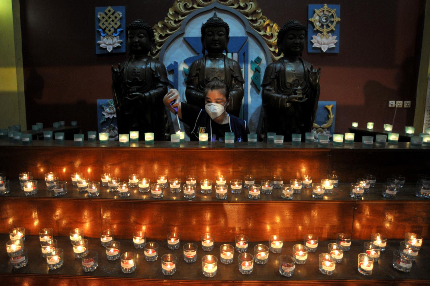 Umat Buddha menyalakan api pelita Waisak, di Vihara Buddha Dharma, Kuta, Bali, Selasa (25/5/2021). Penyalaan ratusan pelita tersebut dilakukan untuk menyambut peringatan Hari Tri Suci Waisak 2565 BE/2021.