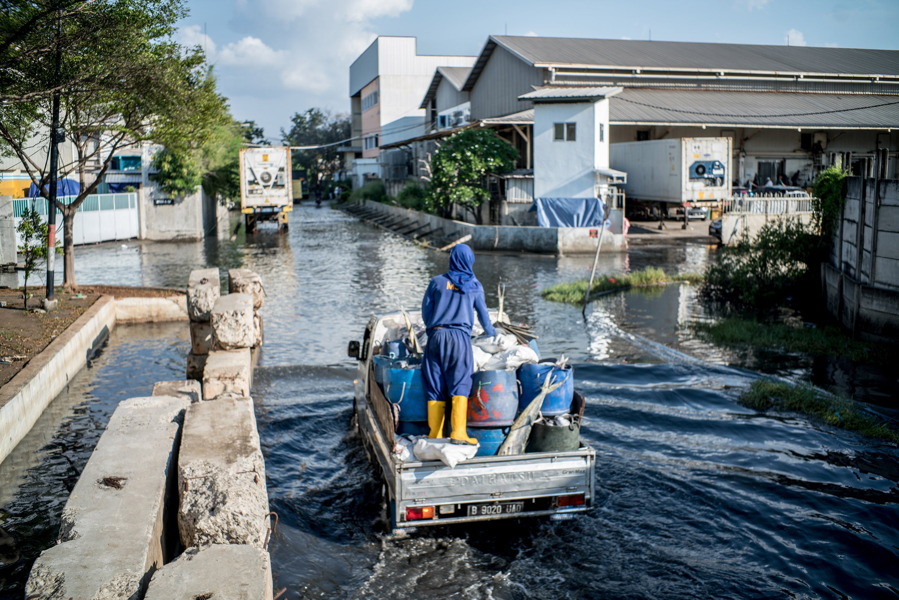 Sejumlah warga melintas di jalan raya Muara Baru yang tergenang banjir rob di Kawasan Muara Baru, Jakarta Utara, Kamis, (27/5/2021). Banjir rob ini terjadi usai fenomena gerhana bulan total atau Super Blood Moon yang berpengaruh terhadap tingginya pasang air laut. Banjir rob ini telah mengenangi jalan dengan ketinggian genangan sekitar 10 centimeter. Meski dilanda banjir rob aktivitas pelabuhan masih tetap berjalan seperti biasa. Potensi banjir rob akibat air pasang di pesisir Jakarta terjadi sepanjang 28