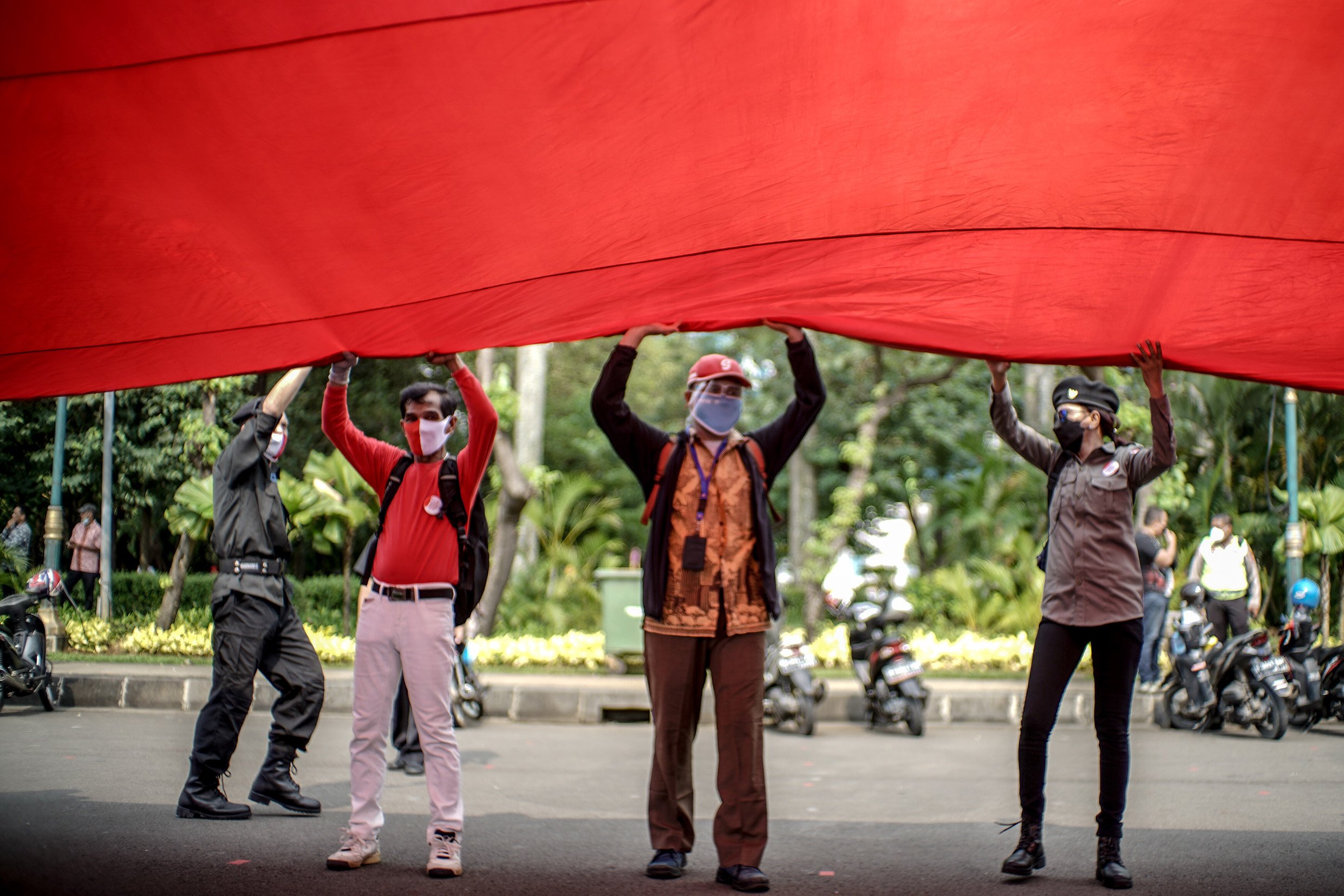 Sejumlah relawan yang tergabung dalam Gerakan Jaga Indonesia (GJI) mengibarkan bendera merah putih raksasa di Patung Kuda, Jalan Merdeka Barat, Jakarta Pusat, Rabu (2/6/2021). Pengibaran bendera merah putih raksasa tersebut dilakukan masa aksi dalam memperingati hari lahir pancasila.
