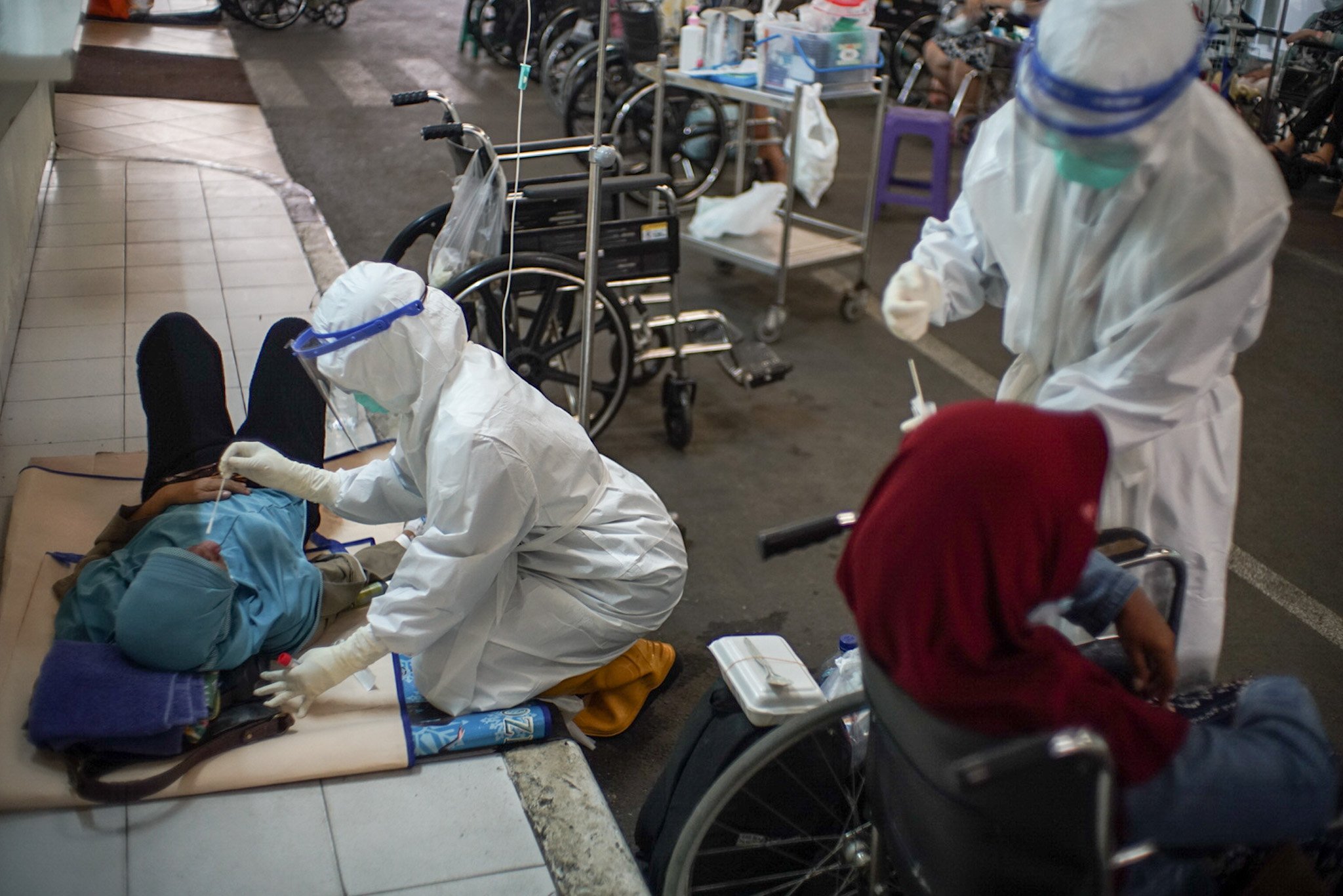 Petugas medis mengenakan Alat Pelindung Diri (APD) lengkap melakukan tes usap pada pasien Covid-19 yang menunggu di pelataran untuk mendapatkan tempat tidur perawatan di IGD RSUD Cengkareng, Jakarta Barat, Rabu, (23/6/2021). Sejak awal bulan Juni 2021 atau setelah libur lebaran hingga saat ini lonjakan pasien positif Covid-19 terus terjadi sehingga rumah sakit kewalahan dan kehabisan tempat perawatan.