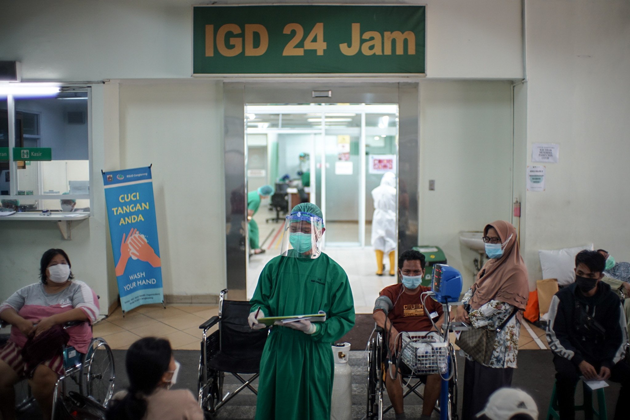 Petugas medis mengenakan Alat Pelindung Diri (APD) lengkap melayani pasien Covid-19 yang menunggu di pelataran untuk mendapatkan tempat tidur perawatan di IGD RSUD Cengkareng, Jakarta Barat, Rabu, (23/6/2021). Sejak awal bulan Juni 2021 atau setelah libur lebaran hingga saat ini lonjakan pasien positif Covid-19 terus terjadi sehingga rumah sakit kewalahan dan kehabisan tempat perawatan.