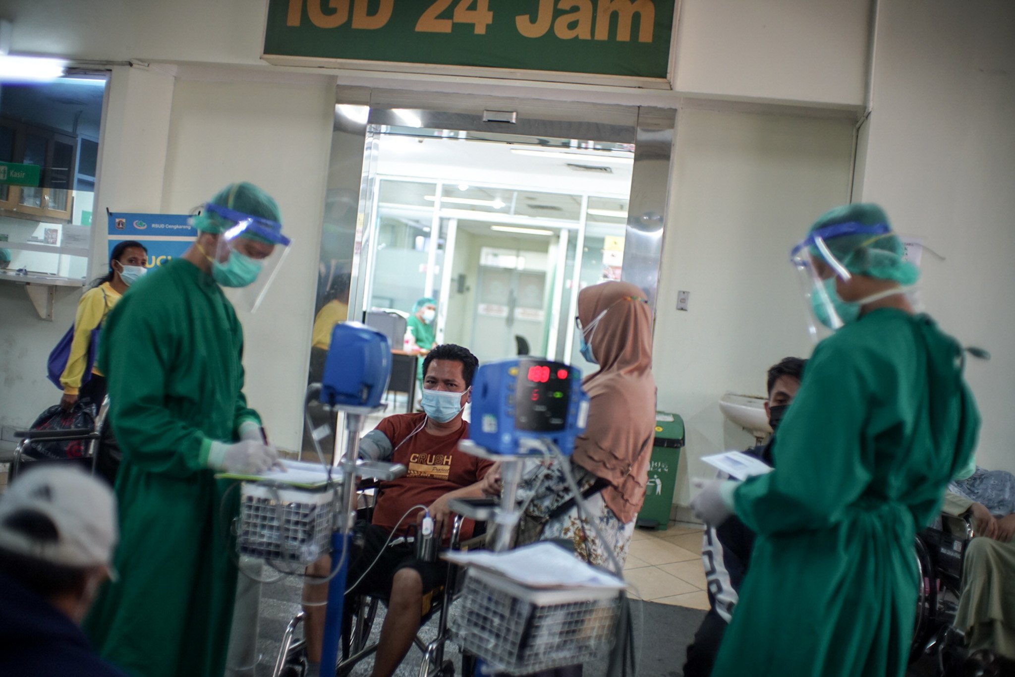Petugas medis mengenakan Alat Pelindung Diri (APD) lengkap merawat pasien Covid-19 yang menunggu di pelataran untuk mendapatkan tempat tidur perawatan di IGD RSUD Cengkareng, Jakarta Barat, Rabu, (23/6/2021). Sejak awal bulan Juni 2021 atau setelah libur lebaran hingga saat ini lonjakan pasien positif Covid-19 terus terjadi sehingga rumah sakit kewalahan dan kehabisan tempat perawatan.