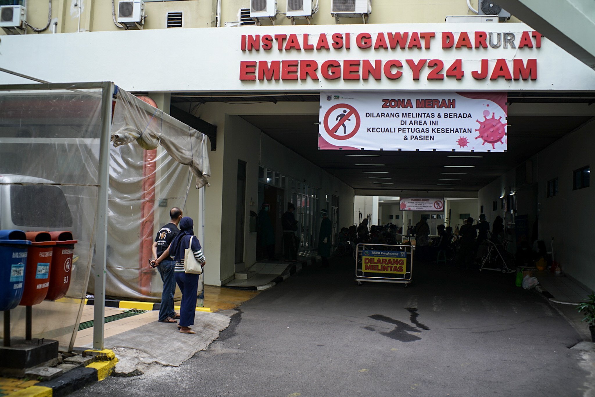 Keluarga korban pasien Covid-19 menunggu di pelataran untuk anggota keluarganya yang terpapar Covid-19 bisa mendapatkan tempat tidur perawatan di IGD RSUD Cengkareng, Jakarta Barat, Rabu, (23/6/2021). Sejak awal bulan Juni 2021 atau setelah libur lebaran hingga saat ini lonjakan pasien positif Covid-19 terus terjadi sehingga rumah sakit kewalahan dan kehabisan tempat perawatan.