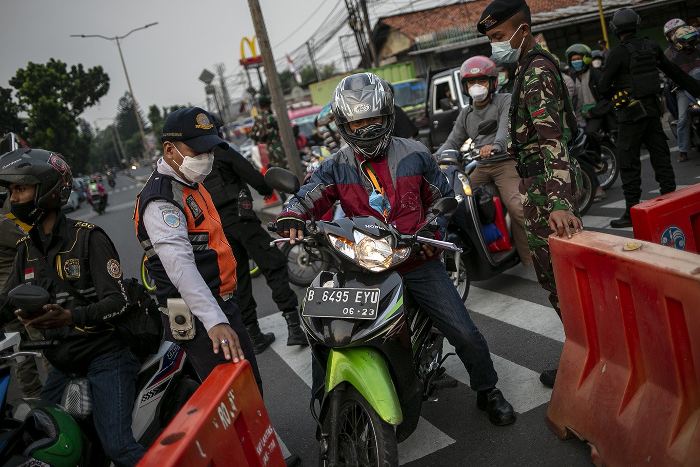 Pasukan gabungan TNI-Polri membuka jalan untuk tenaga kesehatan yang hendak melintas di Jalan Raya Bogor-Jakarta, Depok, Jawa Barat, Selasa, (6/7/2021). Kepadatan arus lalu lintas kendaraan di Pos penyekatan Pemberlakuan Pembatasan Kegiatan Masyarakat (PPKM) Darurat tersebut sudah berkurang hingga 70 persen pada hari ini.