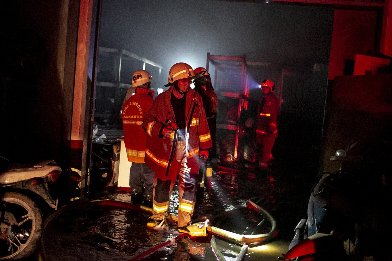 Suku Dinas Penanggulangan Kebakaran dan Penyelamatan (Gulkarmat) mengamati area gudang menggunakan senter usai memadamkan kobaran api yang melahap gudang farmasi di kawasan Cipinang Muara 2, Duren Sawit, Jakarta Timur, Kamis, (8/7/2021). Sebanyak 12 mobil pemadam dan 60 personel dikerahkan untuk memamdamkan kebakaran tersebut.
