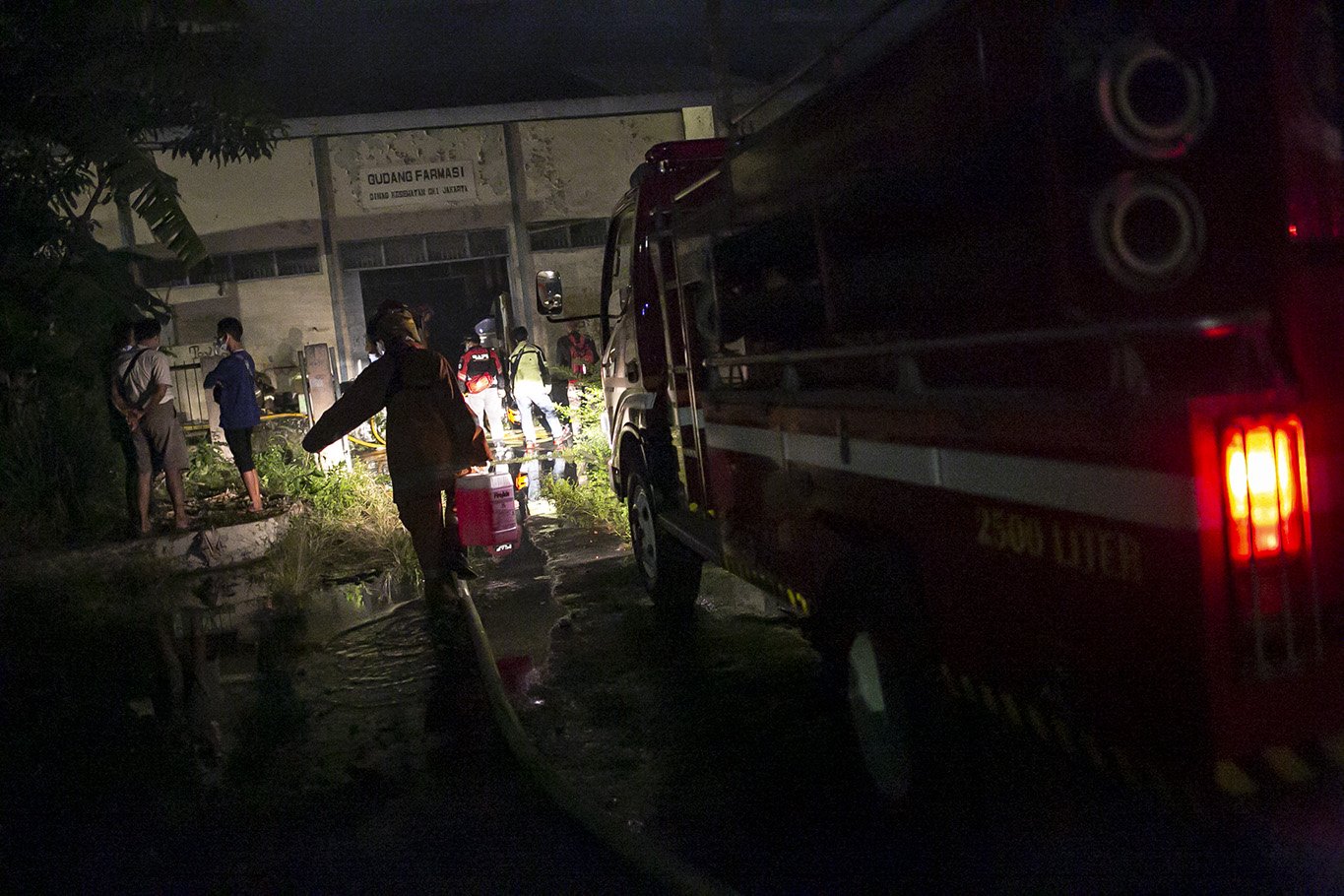 Suku Dinas Penanggulangan Kebakaran dan Penyelamatan (Gulkarmat) membawa jerigen berisi air untuk memadamkan kobaran api yang melahap gudang farmasi di kawasan Cipinang Muara 2, Duren Sawit, Jakarta Timur, Kamis, (8/7/2021). Sebanyak 12 mobil pemadam dan 60 personel dikerahkan untuk memamdamkan kebakaran tersebut.