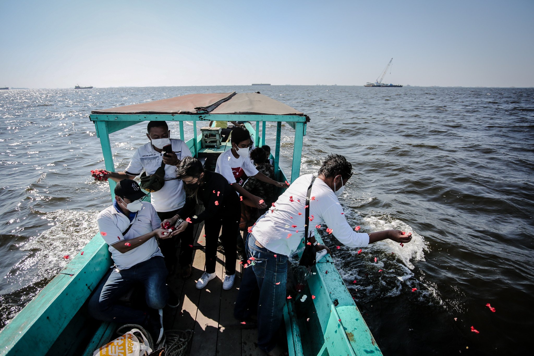 Keluarga mendiang jenazah pasien Covid-19 menabur bunga ke laut usai melarung abu jenazah ke laut Cilincing, Jakarta, Selasa, (27/7/2021).