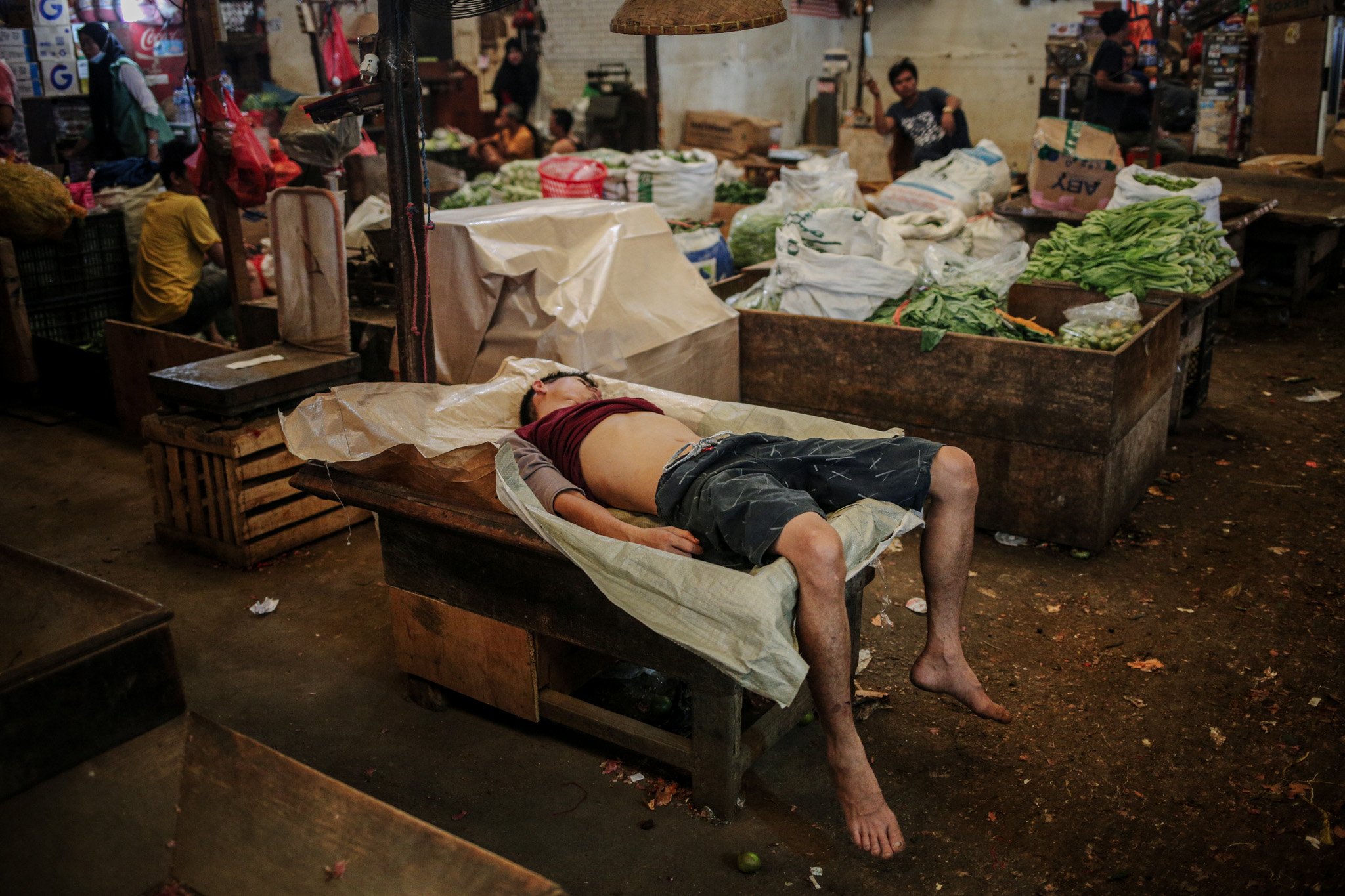Seorang pedagang tertidur lelap di lapak sayur miliknya di Pasar Induk Kramat Jati, Ciracas, Jakarta Timur, Rabu (28/7/2021). 