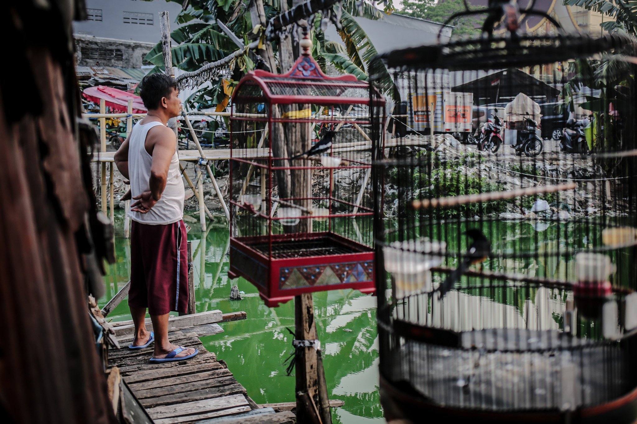 Sejumlah warga beraktivitas di depan rumah panggung miliknya di Kampung Apung, Kapuk, Cengkareng, Jakarta, Kamis, (29/7/2021). Memasuki era 1990an, kampung ini mulai terendam setiap kali hujan besar. Ini merupakan dampak dari berdirinya pabrik-pabrik di sekitar kampung, pabrik-pabrik itu mengunci aliran air ke arah selatan pemukiman warga.