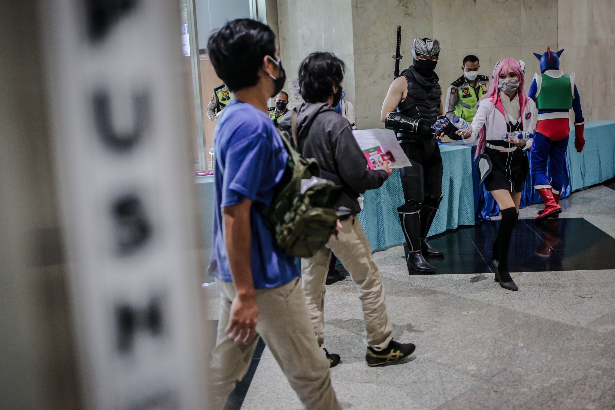 Warga menggunakan kostum cosplay karakter anime jepang membagikan air mineral bagi warga yang hendak menjalani vaskinasi Covid-19 di Jakarta Convention Hall, Jakarta, Sabtu, (31/7/2021). Kementerian Kesehatan mencatat per 31 Juli 2021 jumlah warga yang telah menerima vaksin COVID-19 untuk dosis pertama mencapai 47.226.514 dan dosis kedua mencapai 20.534.823 dari total sararan vaksinasi sebesar 208.265.720.