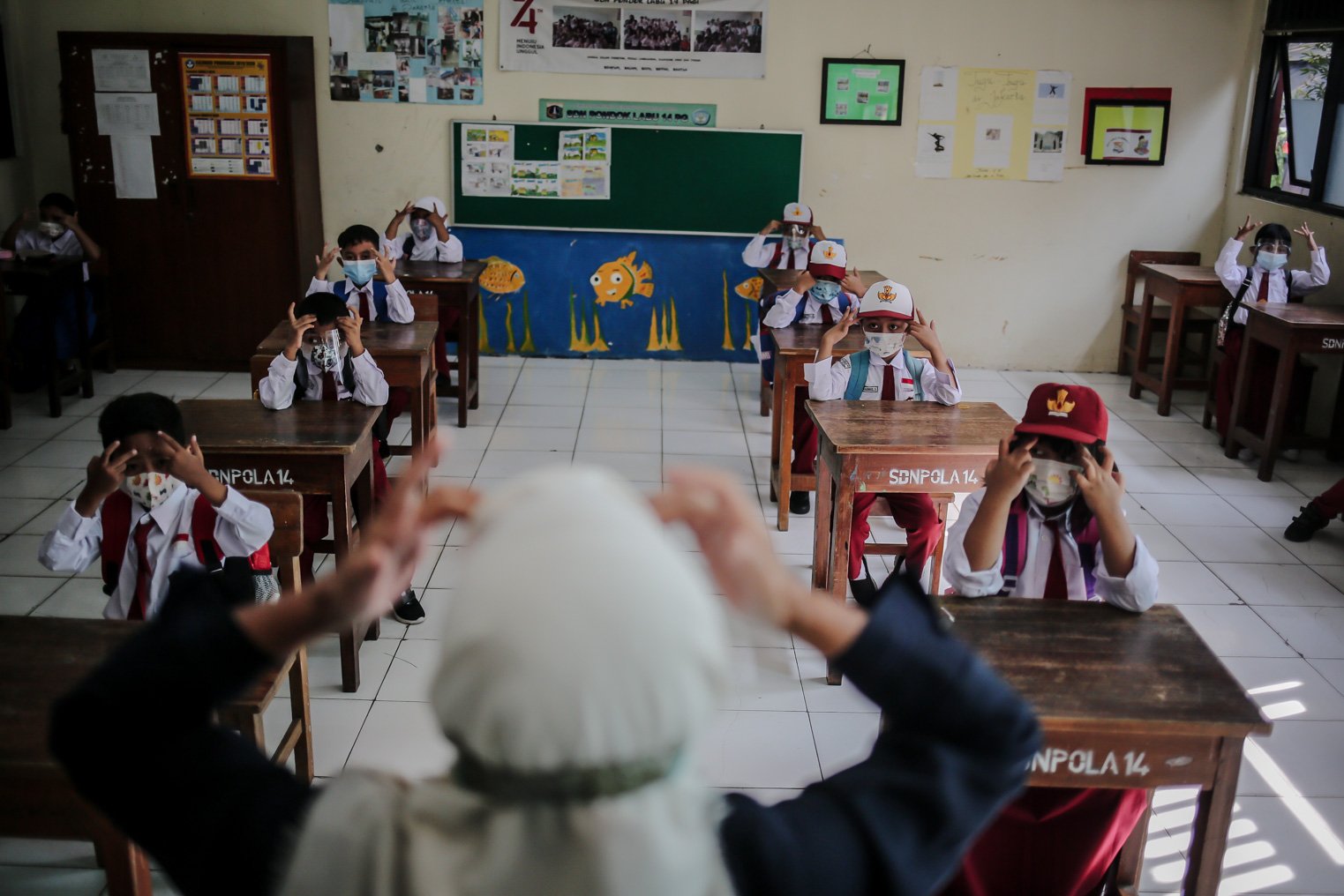 Seorang guru menerangkan mata pelajaran kepada siswa saat kegiatan Pembelajaran Tatap Muka (PTM) perdana dilakukan di Sekolah Dasar Negeri (SDN) Pondok Labu 14 Pagi, Cilandak, Jakarta Selatan, Senin, (30/8/2021). 