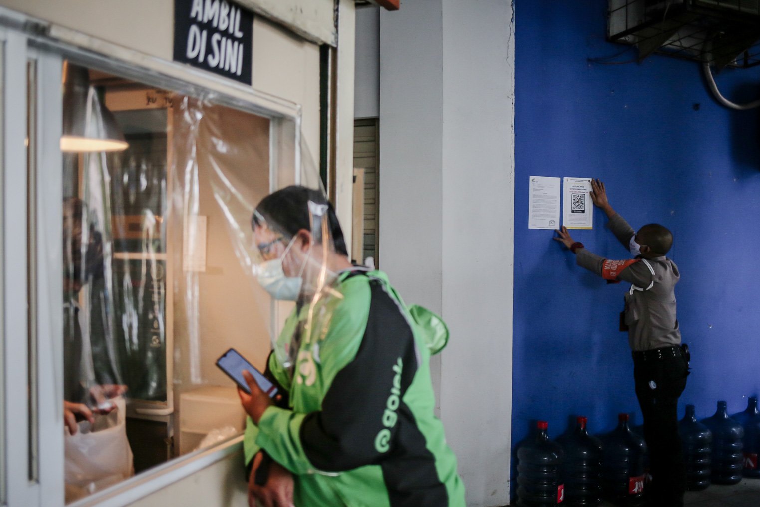 Petugas memasang stiker pengaduan pelanggaran PPKM terpasang di Pasar Santa, Jakarta, Kamis (2/9). Berbagai upaya dilakukan pedagang Pasar Santa untuk menarik pelanggan pada masa PPKM level 3 dengan menasang stiker sertifikat vaksin Covid-19 di beberapa ruko, menyediakan fasilitas disinfektan sebelum masuk pasar, serta mengimbau pedagang dan pengunjung untuk menerapkan protokol kesehatan yang ketat.